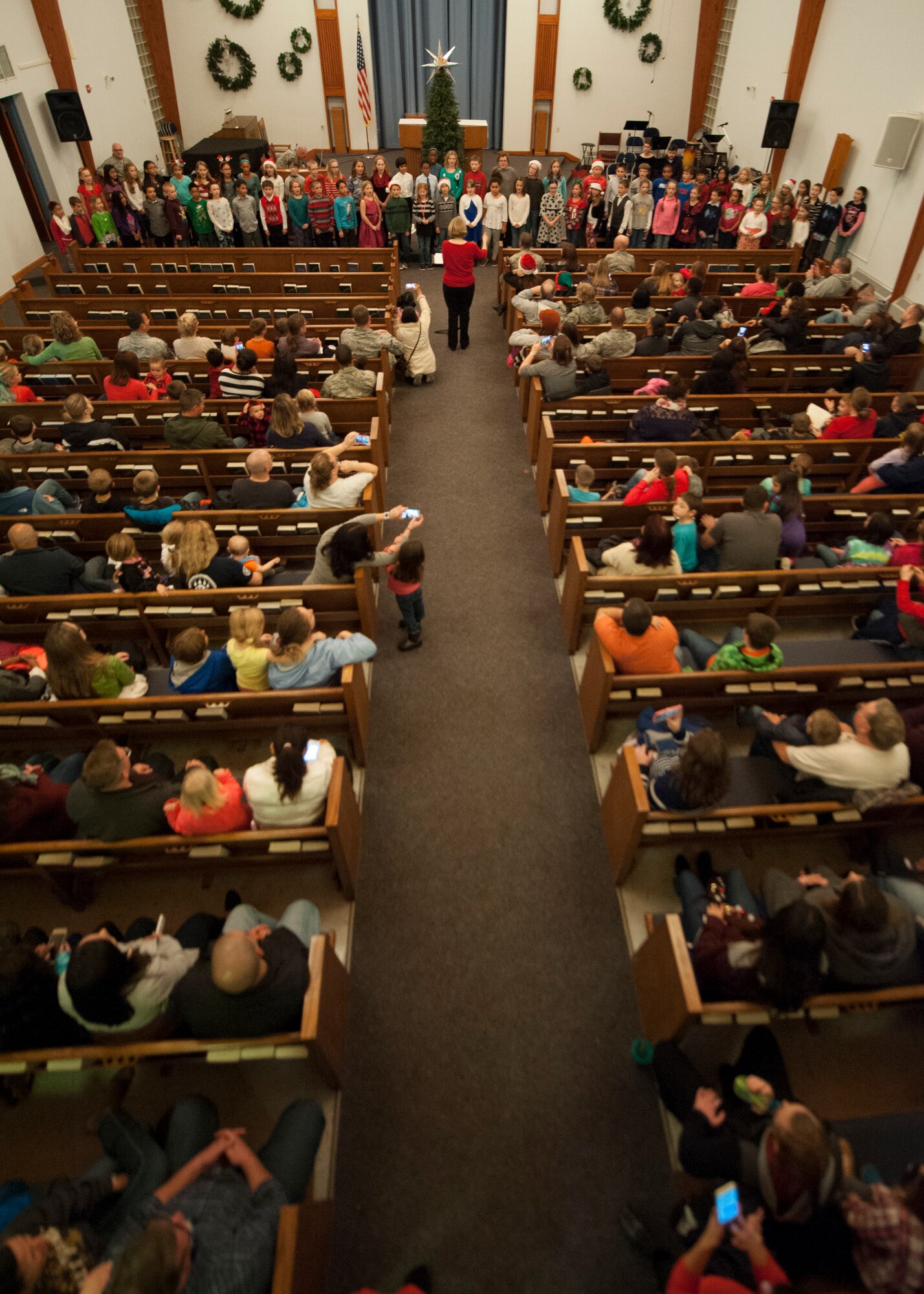 Team Dover Airmen and their families watch the Welsh Elementary School chorus sing carols during the 2015 Dover Air Force Base Holiday Tree Lighting ceremony Dec. 1, 2015, at Chapel 2 on Dover AFB, Del. The event represents the kick off to the holiday season. (U.S. Air Force photo/Senior Airman Zachary Cacicia)