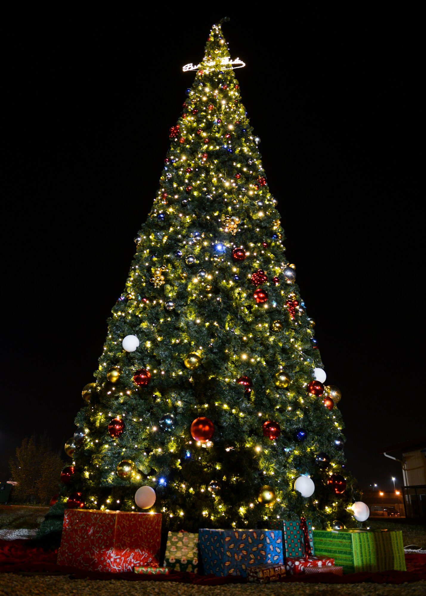 The holiday tree lights up the night sky after the annual holiday tree lighting event, Dec. 1, 2015, at Aviano Air Base, Italy. Santa Claus, Mrs. Claus, helper elves and other holiday celebrities made an appearance and posed with children for photos. (U.S. Air Force photo by Senior Airman Austin Harvill/Released)