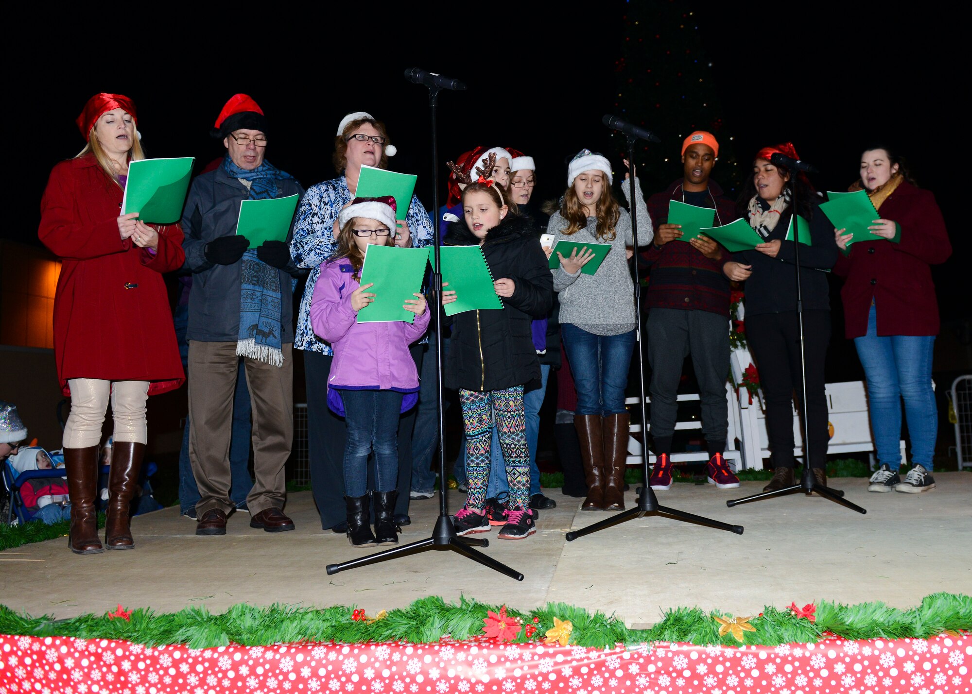 The Aviano Community Theatre sings holiday carols during the annual holiday tree lighting event, Dec. 1, 2015, at Aviano Air Base, Italy. Santa Claus, Mrs. Claus, helper elves and other holiday celebrities made an appearance and posed with children for photos. (U.S. Air Force photo by Senior Airman Austin Harvill/Released)