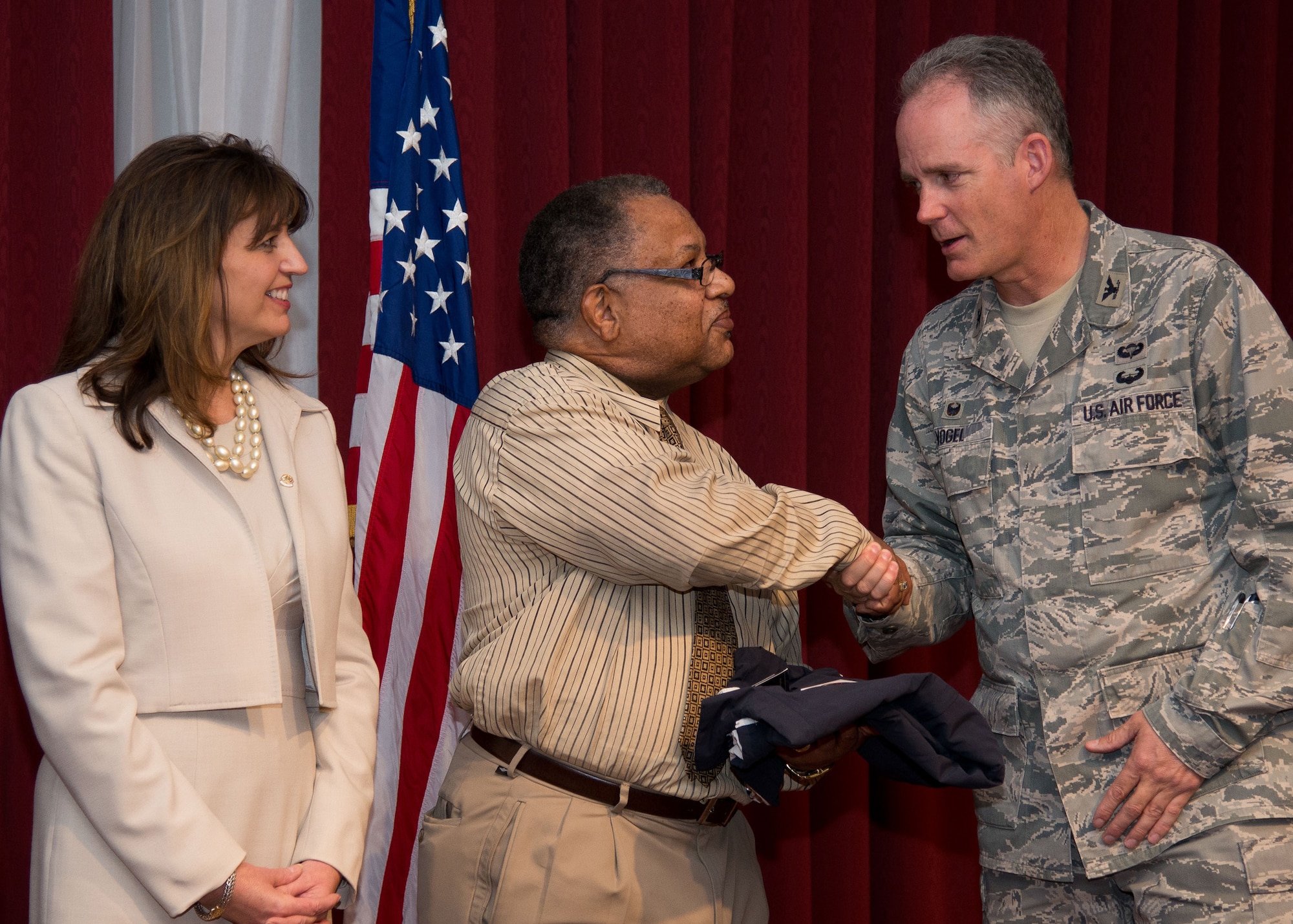 Col. Michael A. Vogel, 66th Air Base Group commander, congratulates Timothy Martin, 66th Air Base Group, on being selected as the Armed Forces Communications and Electronics Association Unsung Hero Award recipient during a reception at the Minuteman Commons Dec. 2, while Maryann Carlson, AFCEA Lexington-Concord Chapter president, looks on. Air Force Life Cycle Management Program Executive Offices, the 66th Air Base Group, Massachusetts National Guard and MITRE each selected a hero who made outstanding contributions to their respective organization in 2015. Other recipients were Linda Grasso, Battle Management Directorate; William Howe, Acquisition Excellence Directorate; Richard Tetreault, C3I and Networks Directorate; U.S. Army Chief Warrant Officer Robert Hallinan, Mass. National Guard; Alan Shoemaker, MITRE. (U.S. Air Force photo by Mark Herlihy)