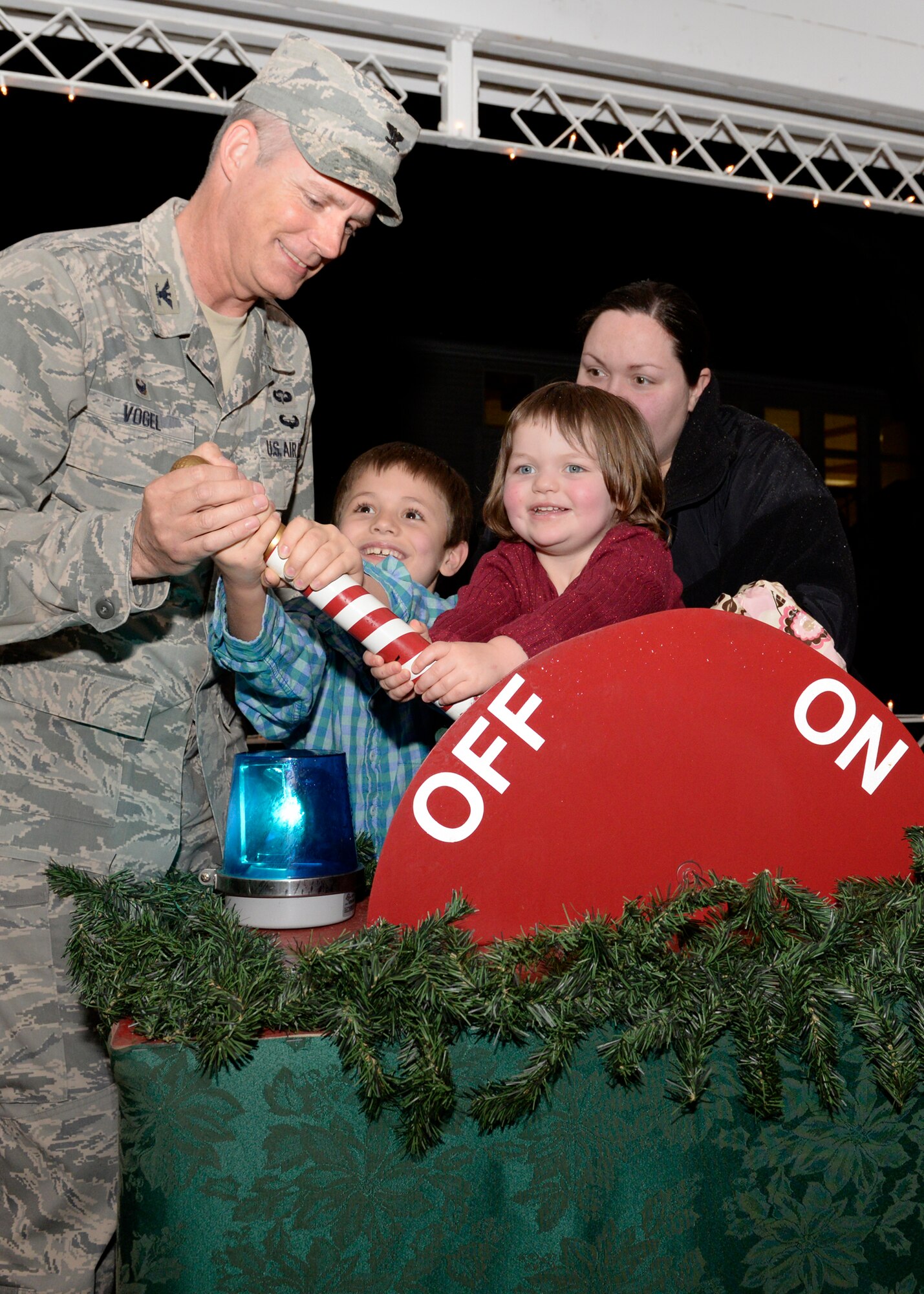 Col. Michael A. Vogel, installation commander, flips the switch with help from Sondra Wiseniske, and her two children, Colin and Katelyn, to turn Christmas tree lights on at the Hanscom Chapel during the annual tree lighting ceremony Dec. 2. The Hanscom Middle School band and choir performed holiday music in the chapel prior to the tree lighting ceremony that was followed by the arrival of Santa. (U.S. Air Force photo by Mark Wyatt)