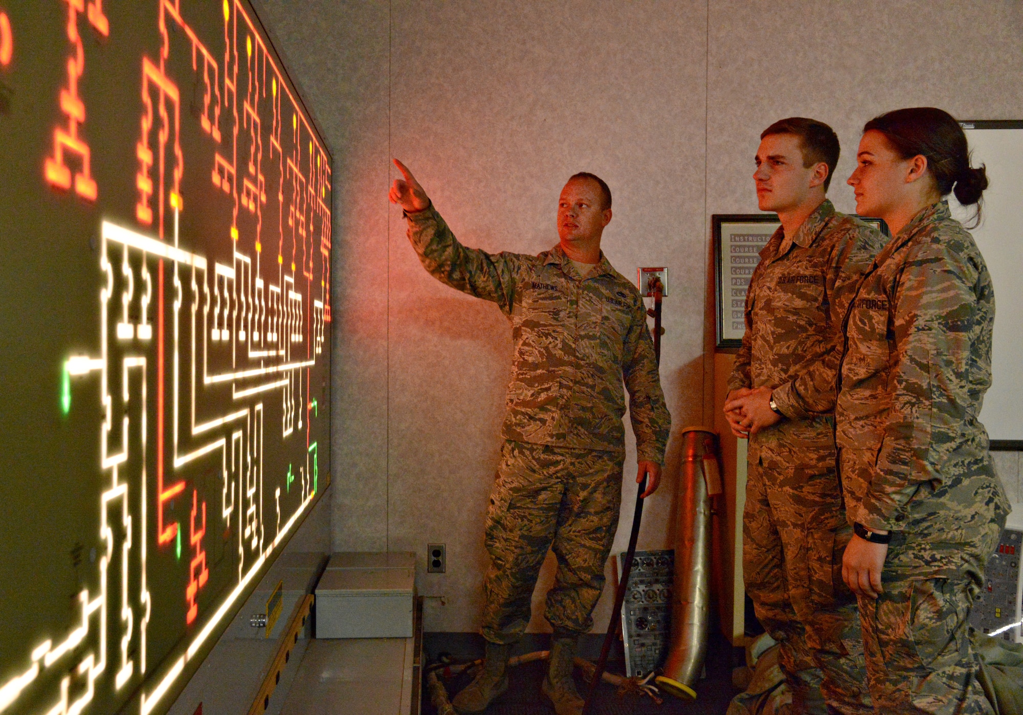 Tech. Sgt. Tyler Mathews, left, an instructor with the 373rd TRS, goes over signal flows on an aircraft generator electrical system with Airman 1st Class Richard Queen and Airman Basic Katherine Thompson, who are both in technical school at the 373rd TRS to become E-3 crew chiefs. (Air Force photo by Kelly White/Released)