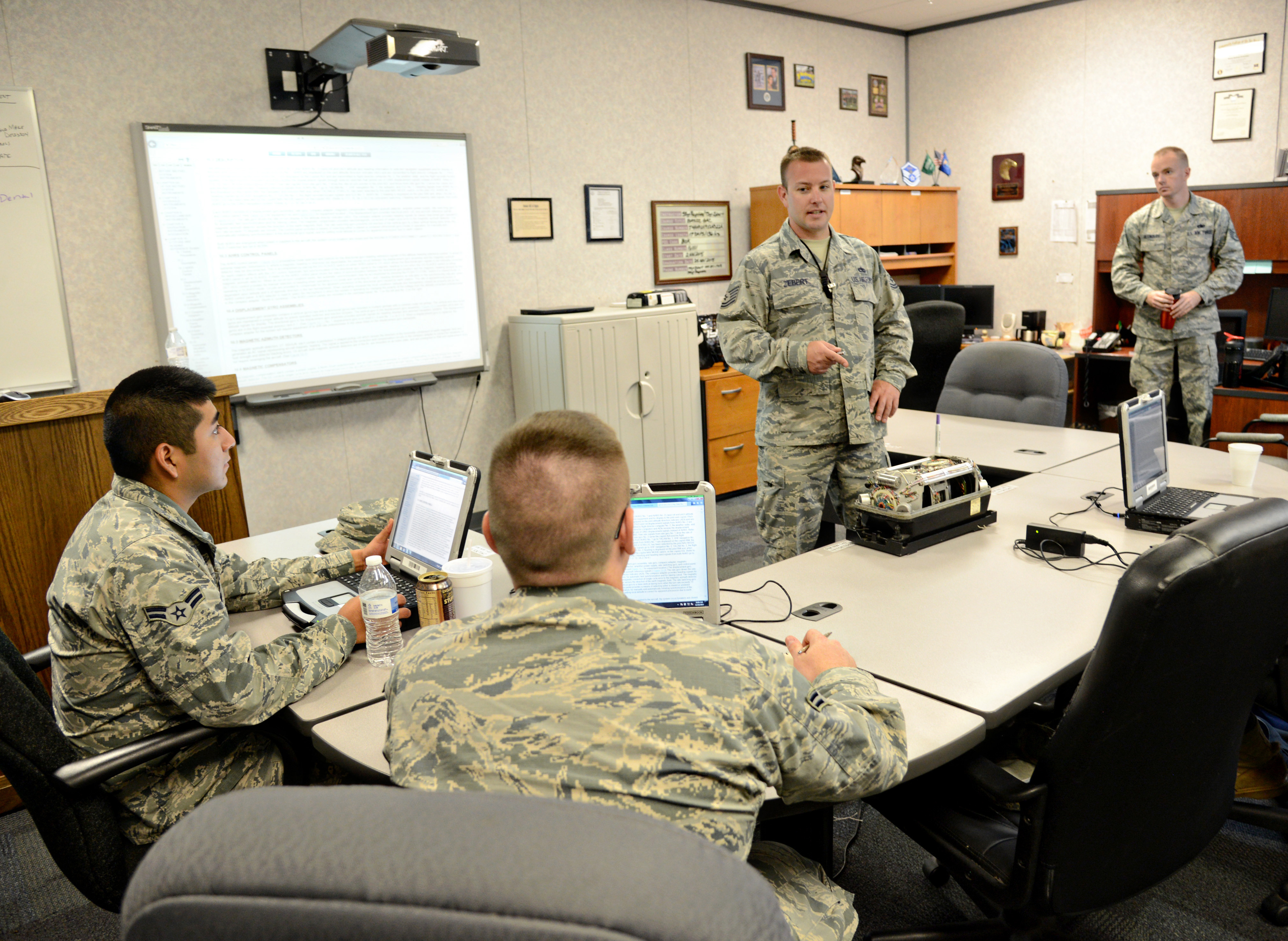 Tech. Sgt. Mitchell Zebert, center, teaches a class to students in the 373rd Training Reserve Squadron. Sergeant Zebert is currently an instructor-in-training and is observed by qualified instructors, such as Staff Sgt. Johnmartin Reynolds, right, during his classes. The instructors will contribute additional information to the students as needed to help him and other instructors-in-training how to more efficiently teach a subject area. (Air Force photo by Kelly White/Released)