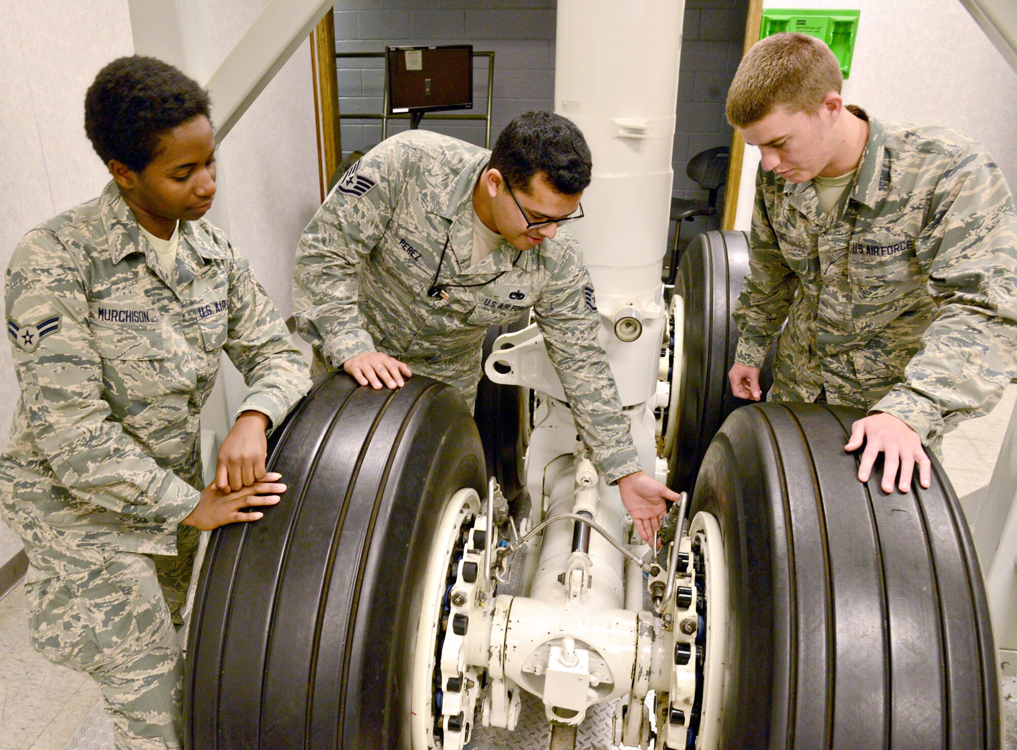 Tech. Sgt. Jorge Perez, center, an instructor with the 373rd Training Reserve Squadron, quizzes Airman 1st Class Basha Murchison, left, and Airman Basic Jacob King about hydraulic lines in the brakes on an E-3 landing gear. Having training equipment of actual aircraft parts available in the 373rd TRS gives students a hands-on learning experience. (Air Force photo by Kelly White/Released)
