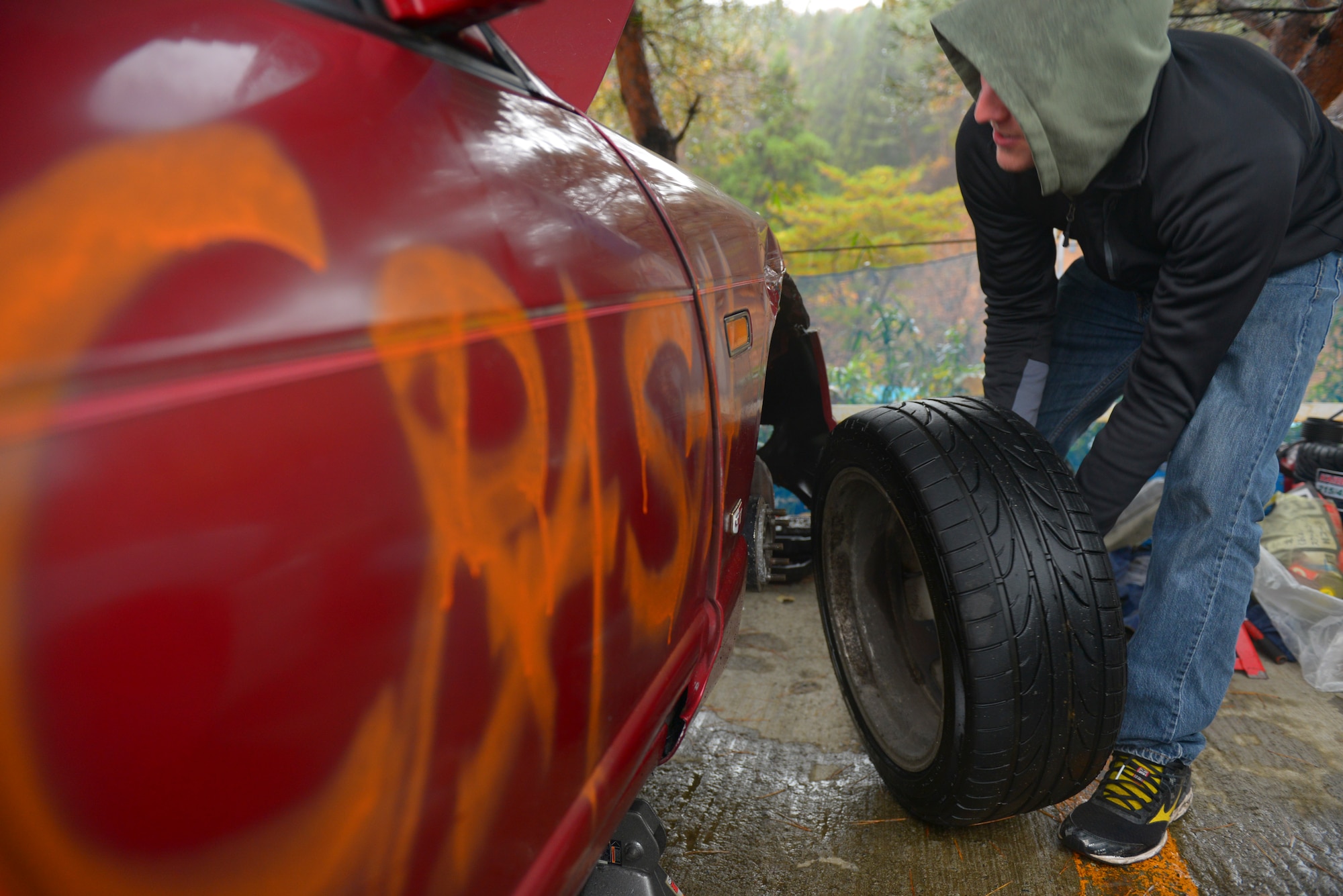 Airman 1st Class Hudson McCormick, 374th Maintenance Squadron hydraulics technician, changes the tire on a drift car at Ebisu Circuit, Japan, Nov. 14, 2015. McCormick and his friends spent many hours repairing the cars between stints on the track, time that was also used for socializing and meeting new people. (U.S. Air Force photo by Airman 1st Class Elizabeth Baker/Released)