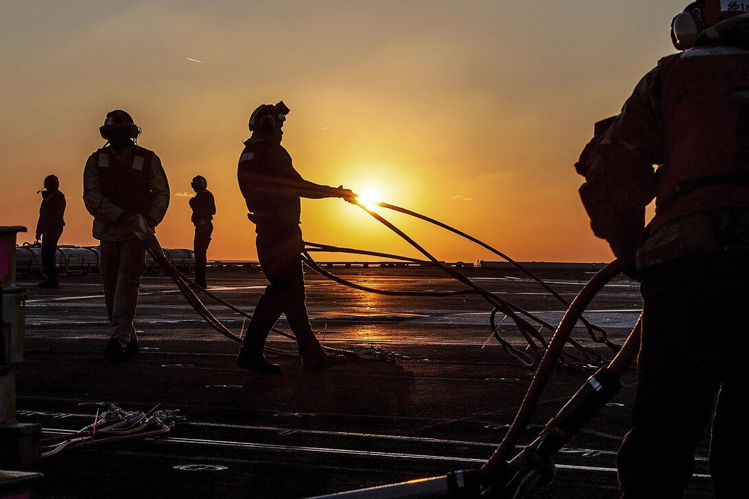 U.S. sailors organize cargo pendants on the flight deck of the U.S. Navy's only forward-deployed aircraft carrier USS Ronald Reagan during an ammunition offload with Military Sealift Command dry cargo and ammunition ship USNS Wally Schirra in the waters south of Japan, Dec. 1, 2015. U.S. Navy photo by Petty Officer 3rd Class Nathan Burke