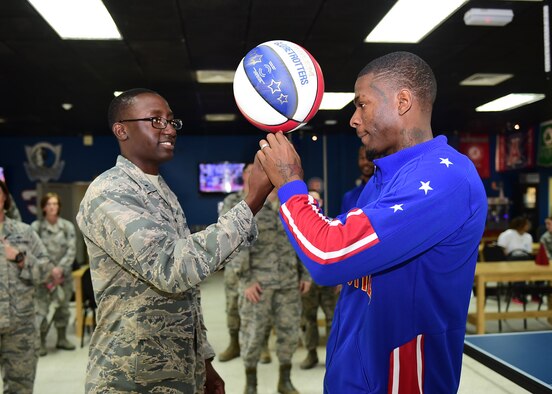 First Lt. Lawrence Thomas, from the 386th Expeditionary Force Support Squadron, spins a basketball on his finger with the help of Harlem Globetrotter “Flip” White at an undisclosed location in Southwest Asia, Nov. 30, 2015. During their visit to the 386th Air Expeditionary Wing, the team put on a show and hosted a meet-and-greet open to all service members deployed in support of Operation INHERENT RESOLVE. (U.S. Air Force photo by Staff Sgt. Jerilyn Quintanilla)