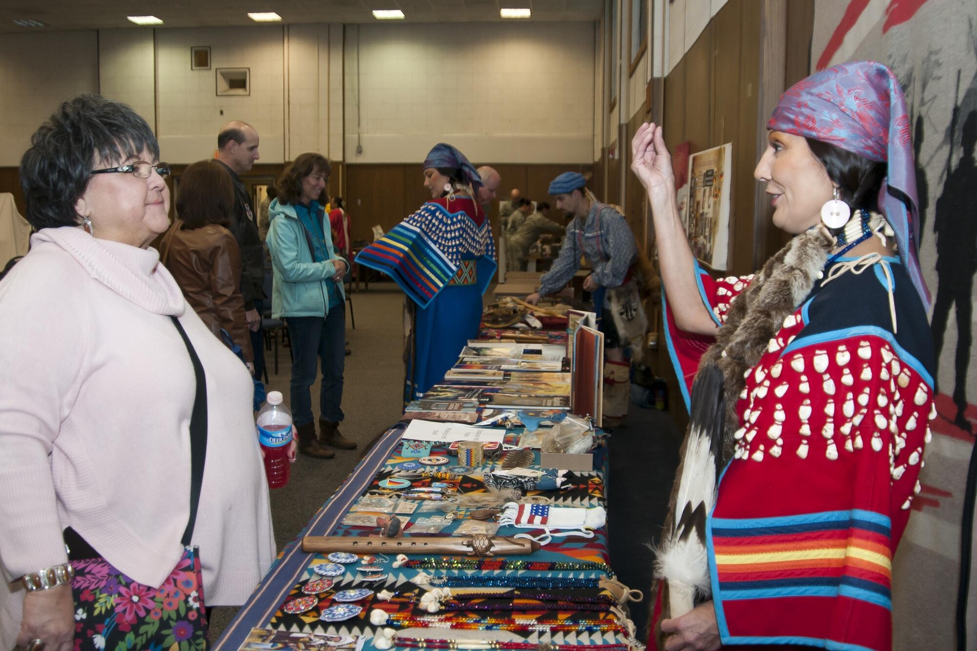 Shirley Alvarez, Shashone Bannock tribe member (right), discusses literature about Native American culture to a guest at the Native American Heritage Month celebration at the 459th Air Refueling Wing auditorium Nov. 30, 2015. The event included traditional food tasting, literature, beadwork, weaponry, music and dancing from half a dozen Native American tribes. (U.S. Air Force photo by Staff Sgt. Kat Justen) 
