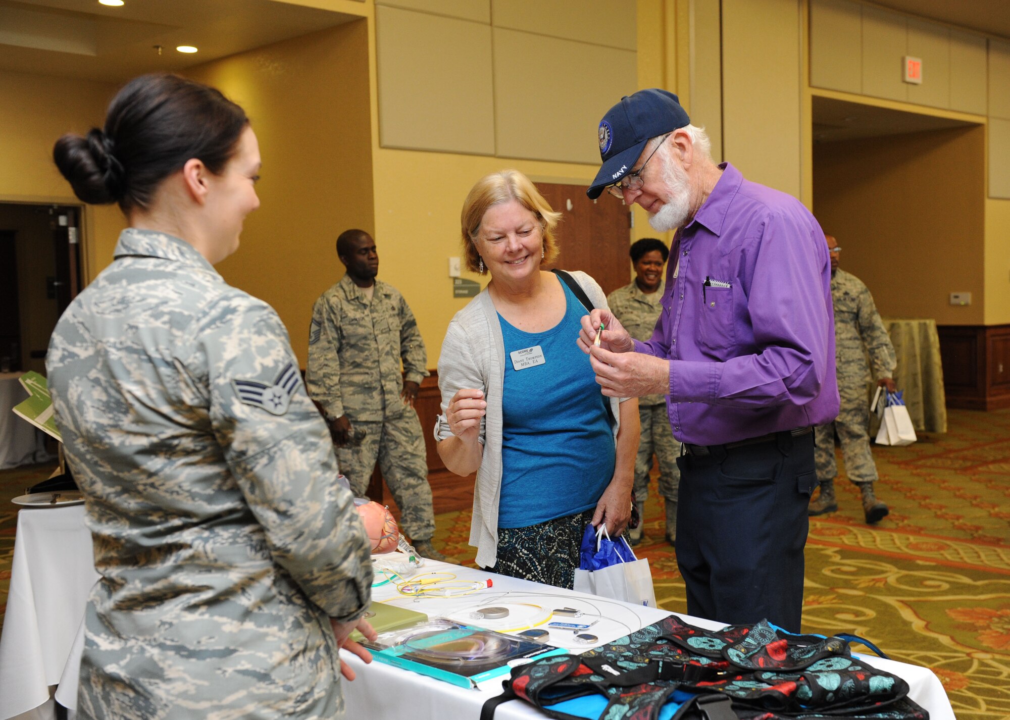 Senior Airman Samantha Roberts, 81st Medical Operations Squadron lab technician, briefs Diane Thompson, SCORE tax advisor, and Louis Finkle, SCORE counselor, on the 81st Medical Group stint program during the Biloxi Chamber of Commerce Morning Call at the Bay Breeze Event Center Dec. 1, 2015, Keesler Air Force Base, Miss. Keesler hosted the event. (U.S. Air Force photo by Kemberly Groue)