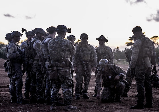 Airmen from the 320th Special Tactics Squadron gather around their team lead outside a shoot house as he discusses details of an upcoming mission Nov. 19, 2015, at Camp Hansen, Japan. Extensive planning and coordination is put into special tactics operations in order to maximize mission effectiveness and safety. (U.S. Air Force photo/Senior Airman John Linzmeier)