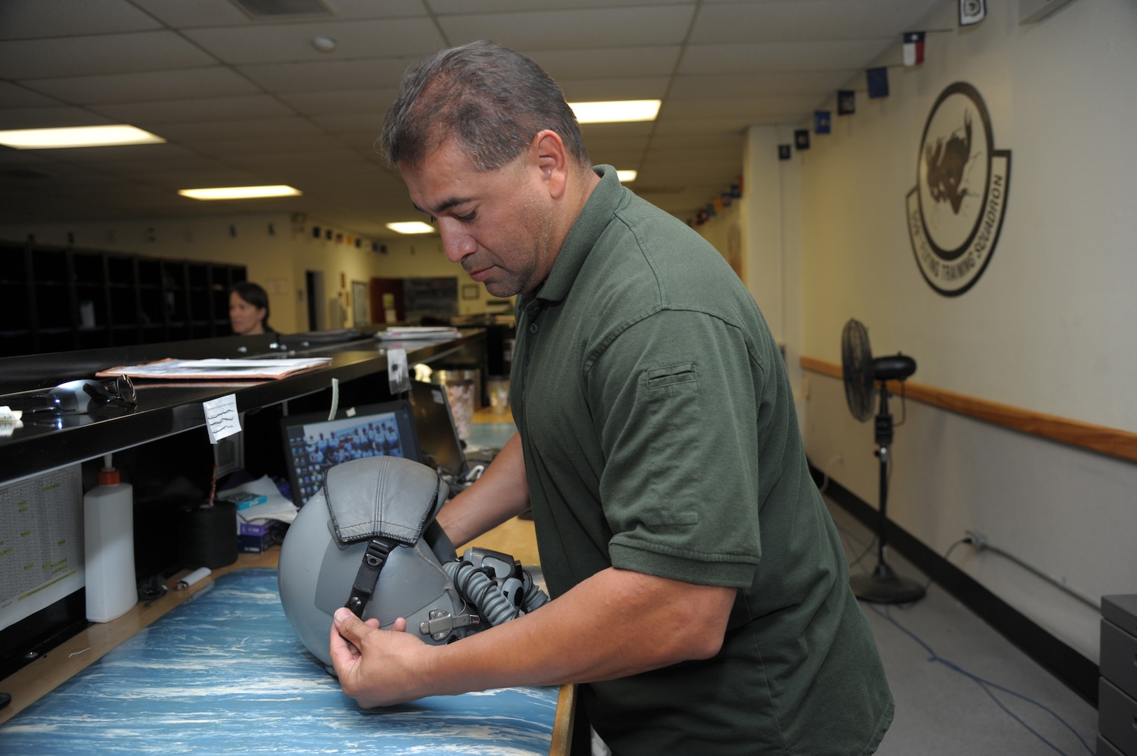 Daniel Guerra, 12th Operations Support Squadron, aircrew flight equipment technician, inspects a helmet, at Joint Base San Antonio-Randolph, Nov. 18, 2015. The 12th OSS is responsible for pilot instructor training and introduction to fighter fundamentals academic and simulator training, scheduling, air traffic control, airfield management, flight records, registrar, weather, airspace management, international training and aircrew flight equipment for all 12th Operational Group training.  (U.S. Air Force photo by Joel Martinez/Released)