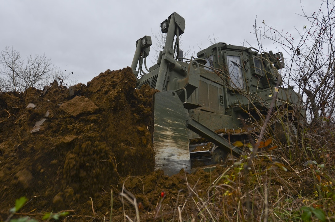 U.S. Army Cpl. Jonathan Norris operates a T9 Dozer to dig a hull-down position for an M1A2 Abrams Tank during Exercise Peace Sentinel at Novo Selo Training Center, Bulgaria, Nov. 23, 2015. Norris is a heavy equipment operator assigned to the 3rd Infantry Division’s 5th Squadron, 7th Cavalry Regiment. U.S. Army photo by Staff Sgt. Steven M. Colvin