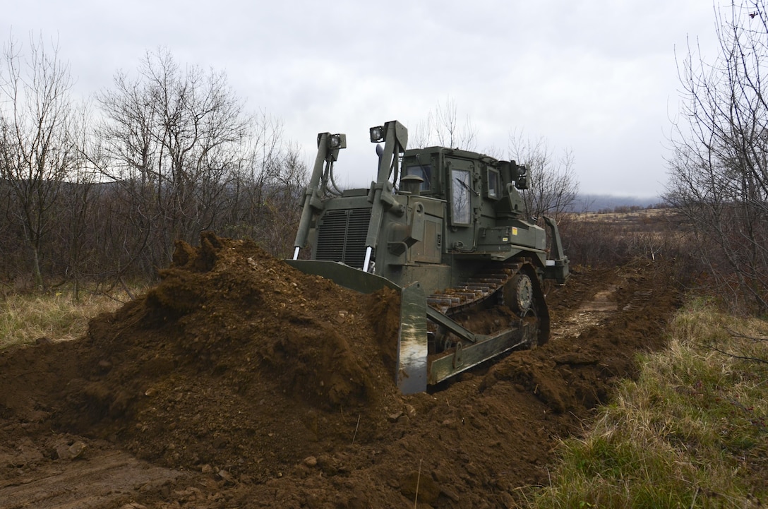 U.S. Army Cpl. Jonathan Norris operates a T9 Dozer to dig a hull-down position for an M1A2 Abrams Tank during Exercise Peace Sentinel at Novo Selo Training Center, Bulgaria, Nov. 23, 2015. Norris is a heavy equipment operator assigned to the 3rd Infantry Division’s 5th Squadron, 7th Cavalry Regiment. U.S. Army photo by Staff Sgt. Steven M. Colvin