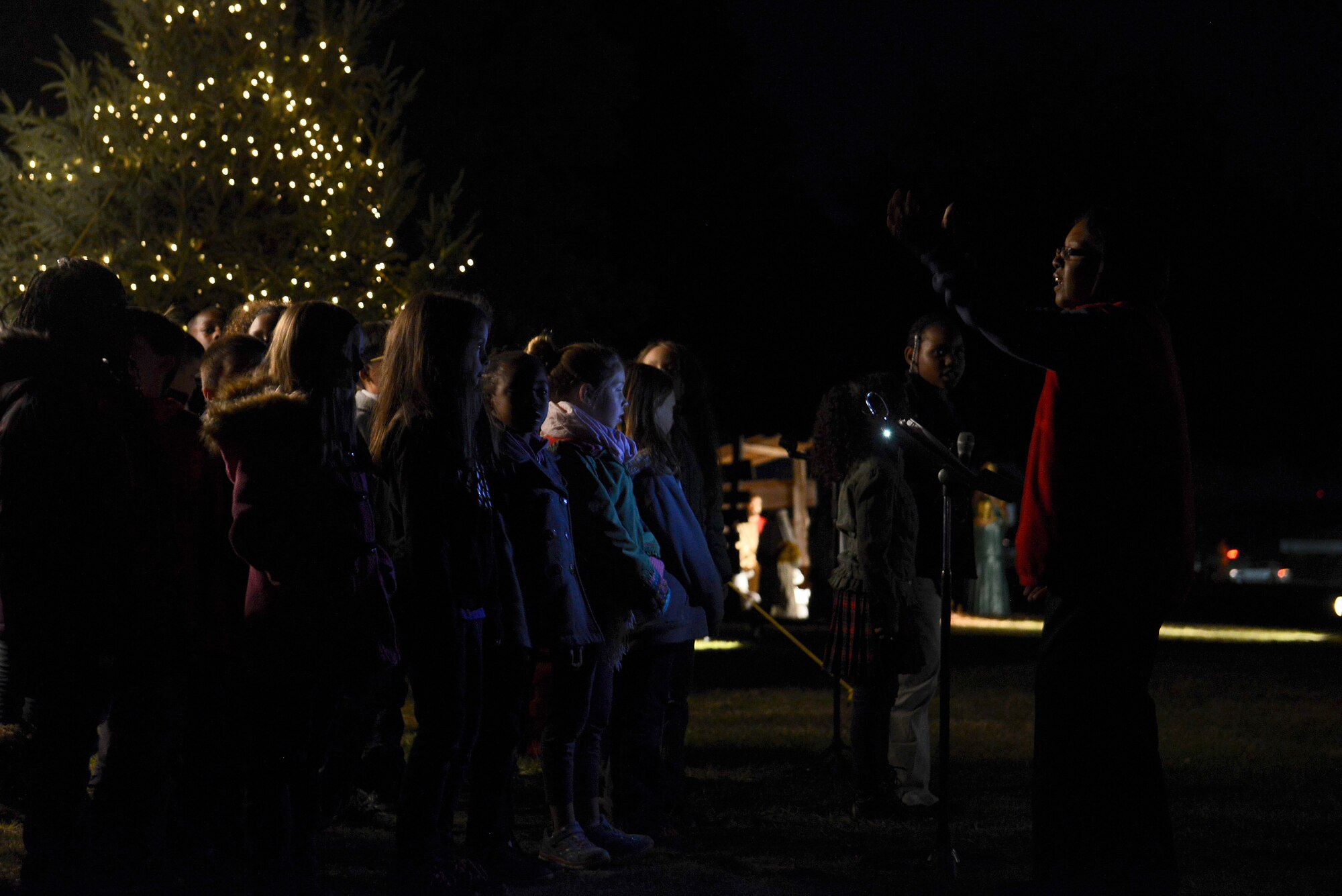 Shaw Heights Elementary School choir sings holiday songs during a Christmas Tree Lighting/Religious Display Interfaith Ceremony at the Friendship Chapel, Dec. 3, 2015, at Shaw Air Force Base, S.C., Dec. 3, 2015. The evening began with a performance from the Shaw Heights Elementary School choir followed by the religious display and tree lighting. (U.S. Air Force photo by Airman 1st Class Christopher Maldonado) 