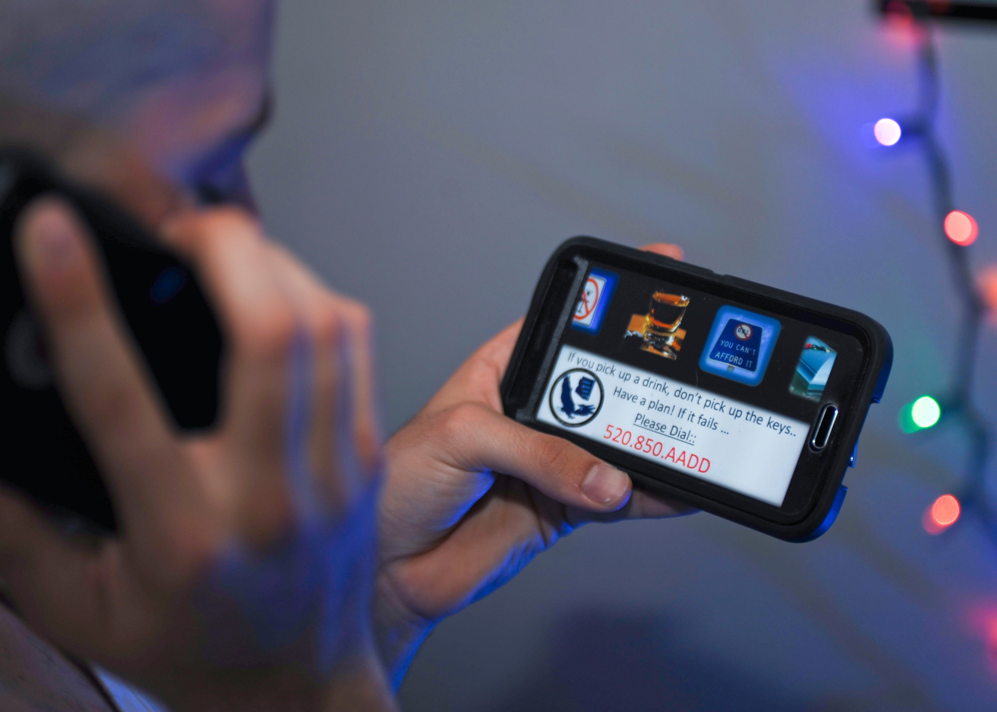 A U.S. Airman checks his phone for the number to Airmen Against Drunk Driving at Davis-Monthan Air Force Base, Ariz., Nov. 30, 2015. The service is available 10 p.m. to 3 a.m. Fridays and Saturdays for anyone in a 20-mile-radius of the base with a military ID card. To request a ride, call (520) 228-2233 or (520) 850-2233. (U.S. Air Force photo by Airman Basic Nathan H. Barbour/Released)