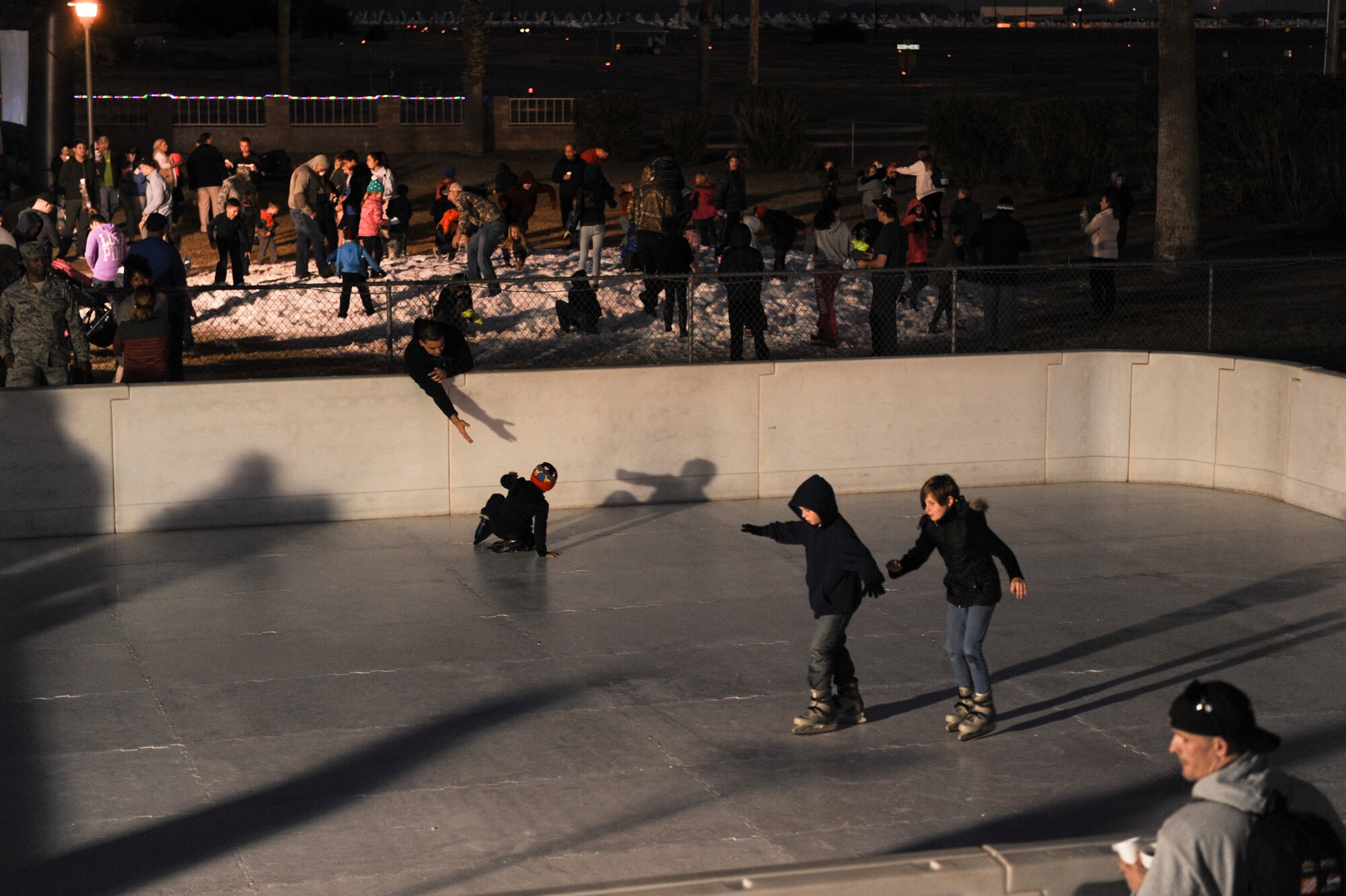 Children skate around an ice rink during the Starry, Snowy, Southwest Night event at Davis-Monthan Air Force Base, Ariz., Dec. 3, 2015. Sixty tons of snow were divided into two areas for people of all ages to play in and free hot chocolate and cookies were available. (U.S. Air Force photo by Airman Basic Nathan H. Barbour/Released)