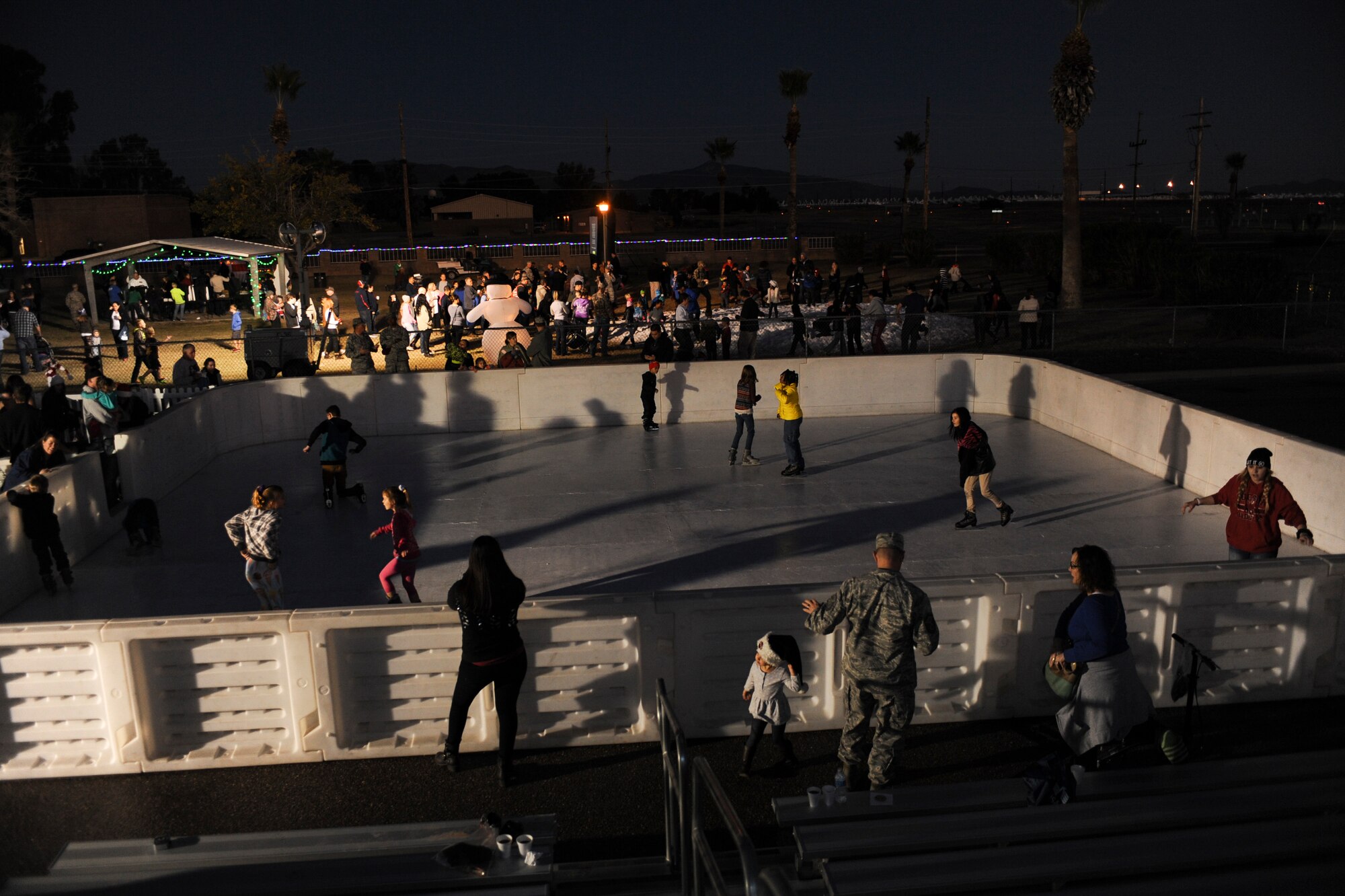 Children skate around an ice rink during the Starry, Snowy, Southwest Night event at Davis-Monthan Air Force Base, Ariz., Dec. 3, 2015. Sixty tons of snow were divided into two areas for people of all ages to play in and free hot chocolate and cookies were available. (U.S. Air Force photo by Airman Basic Nathan H. Barbour/Released)