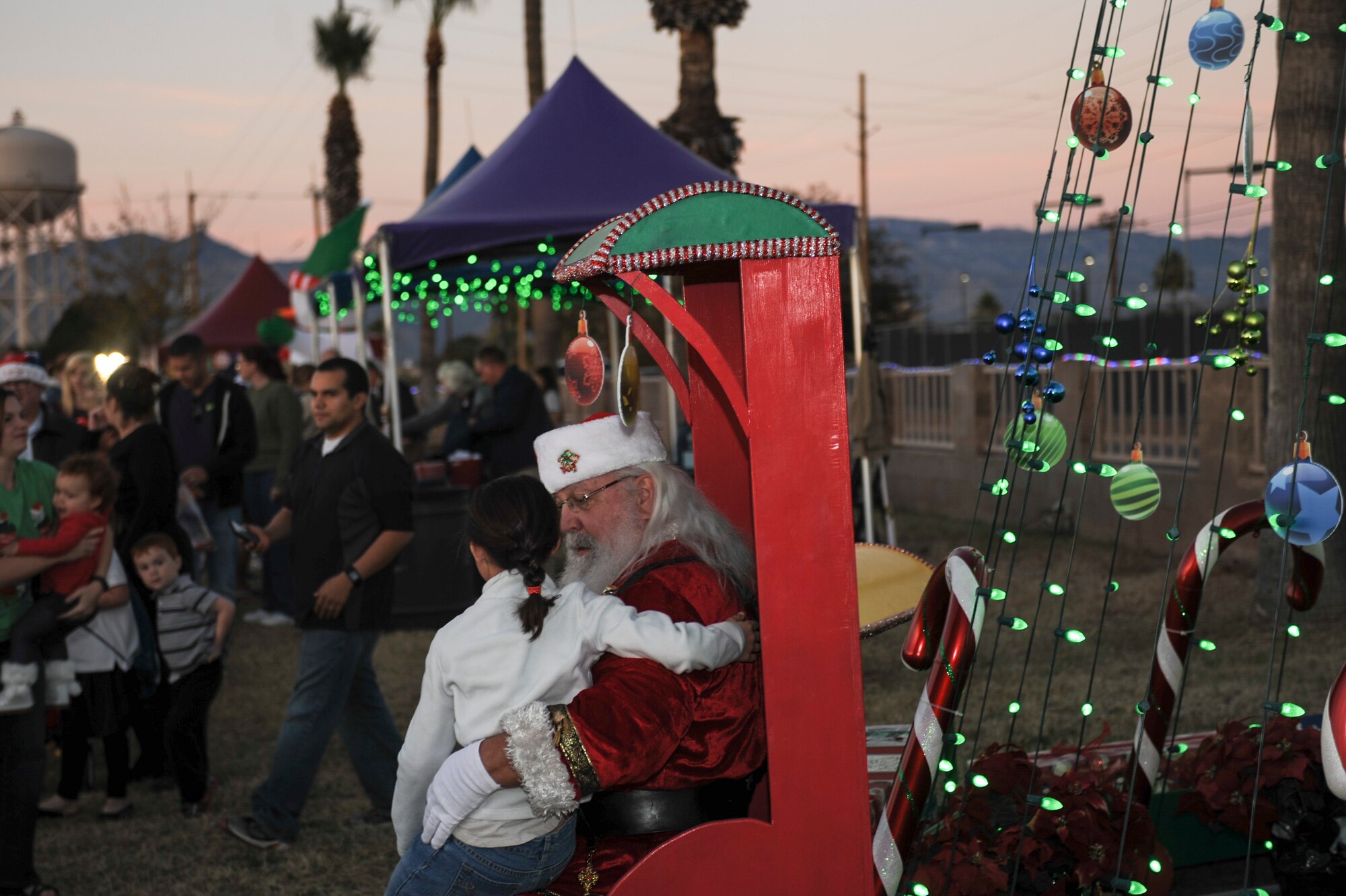 A child sits on Santa Claus’ lap during the Starry, Snowy, Southwest Night event at Davis-Monthan Air Force Base, Ariz., Dec. 3, 2015. Volunteers organized festivities that included photos with Santa, story time with Buddy the Elf, a mechanical snowboard and 60 tons of snow.  (U.S. Air Force photo by Airman Basic Nathan H. Barbour/Released)