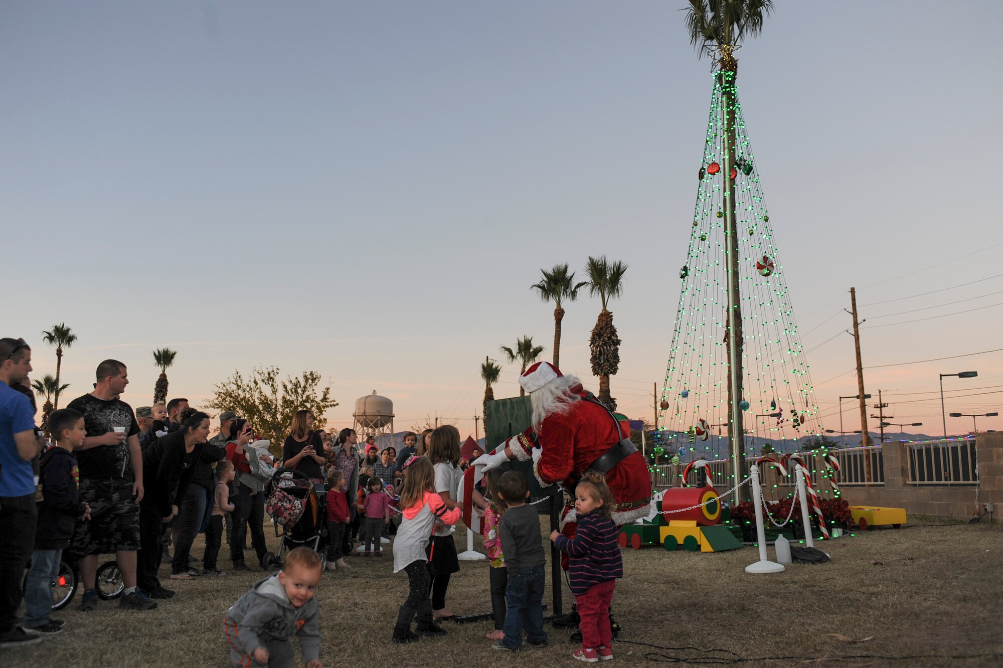 Children of deployed Airmen assist Santa Claus in turning on the tree of lights during the Starry, Snowy, Southwest Night event at Davis-Monthan Air Force Base, Ariz., Dec. 3, 2015. Volunteers organized festivities that included photos with Santa, story time with Buddy the Elf, a mechanical snowboard and 60 tons of snow. (U.S. Air Force photo by Airman Basic Nathan H. Barbour/Released)