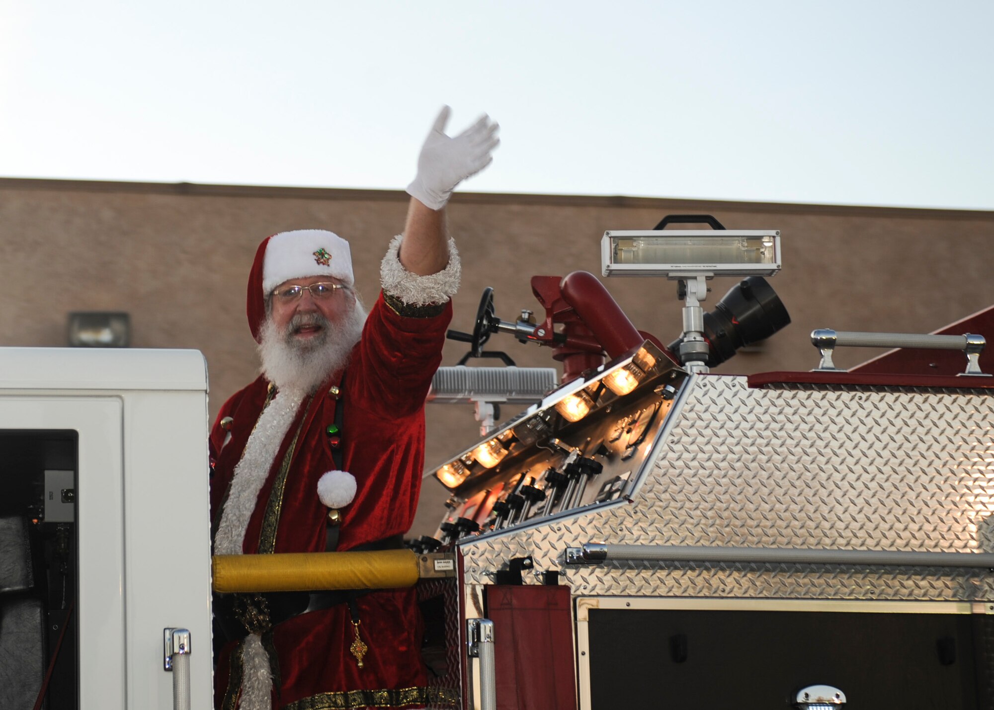 Santa Claus arrives on a fire truck during the Starry, Snowy, Southwest Night event at Davis-Monthan Air Force Base, Ariz., Dec. 3, 2015. Volunteers organized festivities that included photos with Santa, story time with Buddy the Elf, a mechanical snowboard and 60 tons of snow. (U.S. Air Force photo by Airman Basic Nathan H. Barbour/Released)
