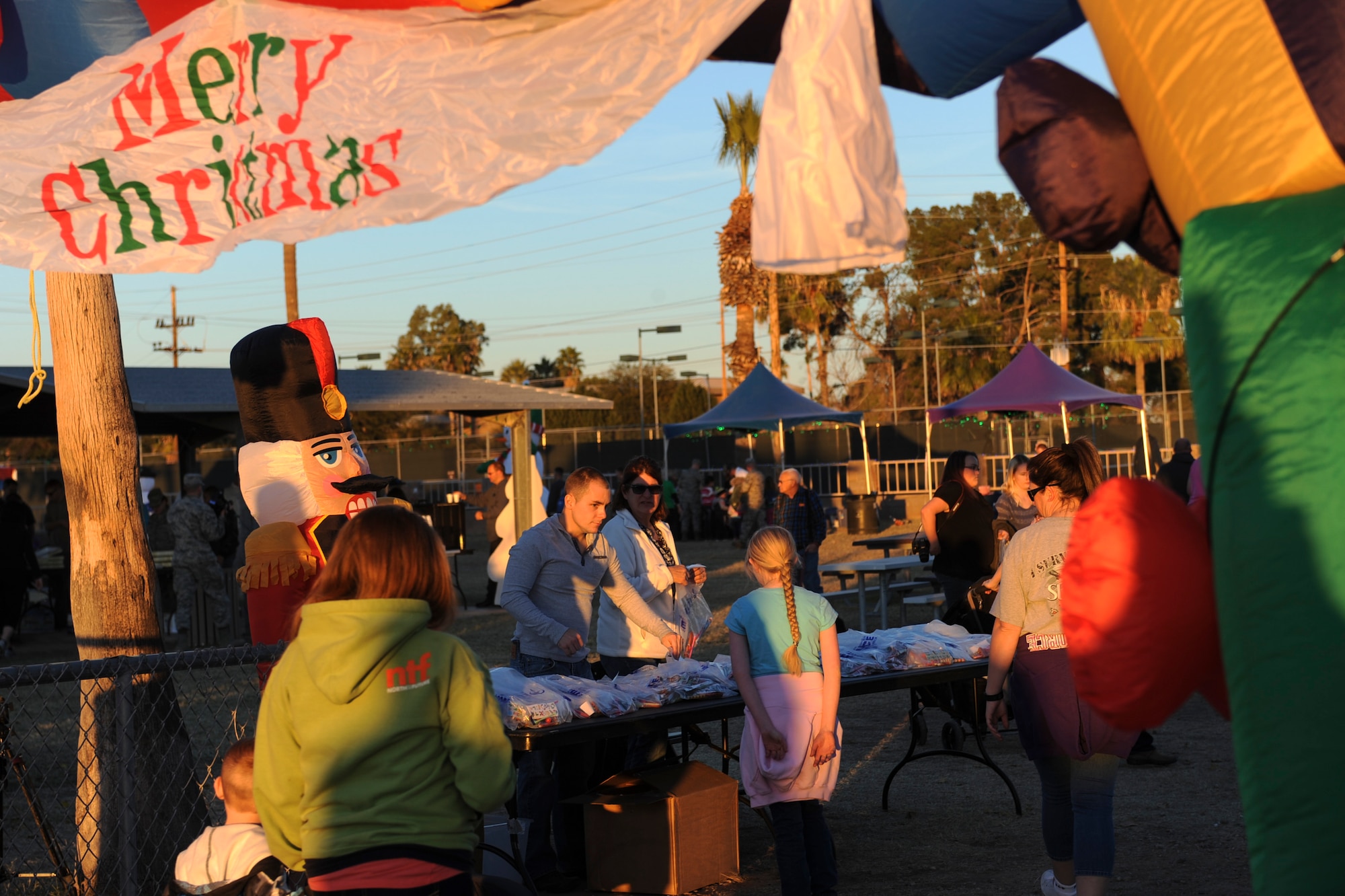 Volunteers welcome and hand out goody bags to attendees of the Starry, Snowy, Southwest Night event at Davis-Monthan Air Force Base, Ariz., Dec. 3, 2015. The annual event was organized by the 355th Force Support Squadron and Outdoor Recreation and approximately 30 volunteer Airmen assisted during the event. (U.S. Air Force photo by Airman Basic Nathan H. Barbour/Released)