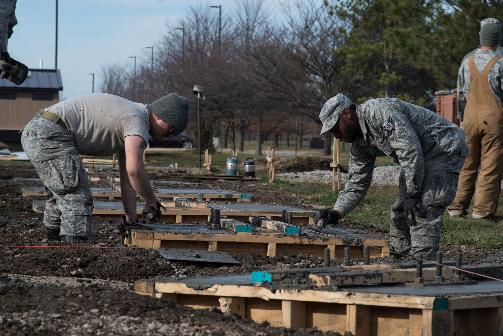Airmen from the Civil Engineering Squadron poor concrete for the new pavilion by the James Gym track November 24, 2015 at Scott Air Force base Illinois. The pavilion will offer sit-up and pull-up bars to offer an established physical training area protected from the weather. (U.S. Air Force photo by Airman Gwendalyn Smith)