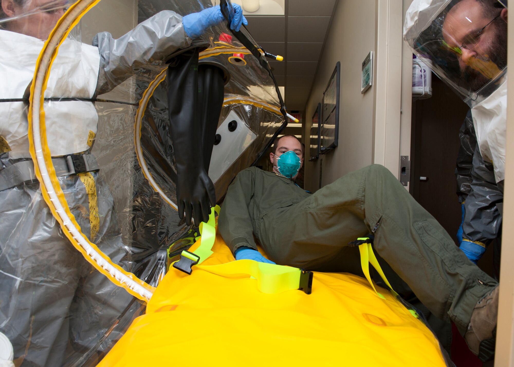 Brett Zingarelli and Brittany Farra, St. Francis Healthcare emergency medical technicians, assist Senior Airman Peter Cannizzaro, 9th Airlift Squadron loadmaster, into a single patient bio-containment unit (isolation pod) Nov. 3, 2015, in the 436th Medical Group Clinic on Dover Air Force Base, Del. The isolation pod’s purpose is to isolate a patient from other individuals to prevent the spread of disease. (U.S. Air Force photo/Senior Airman Zachary Cacicia)