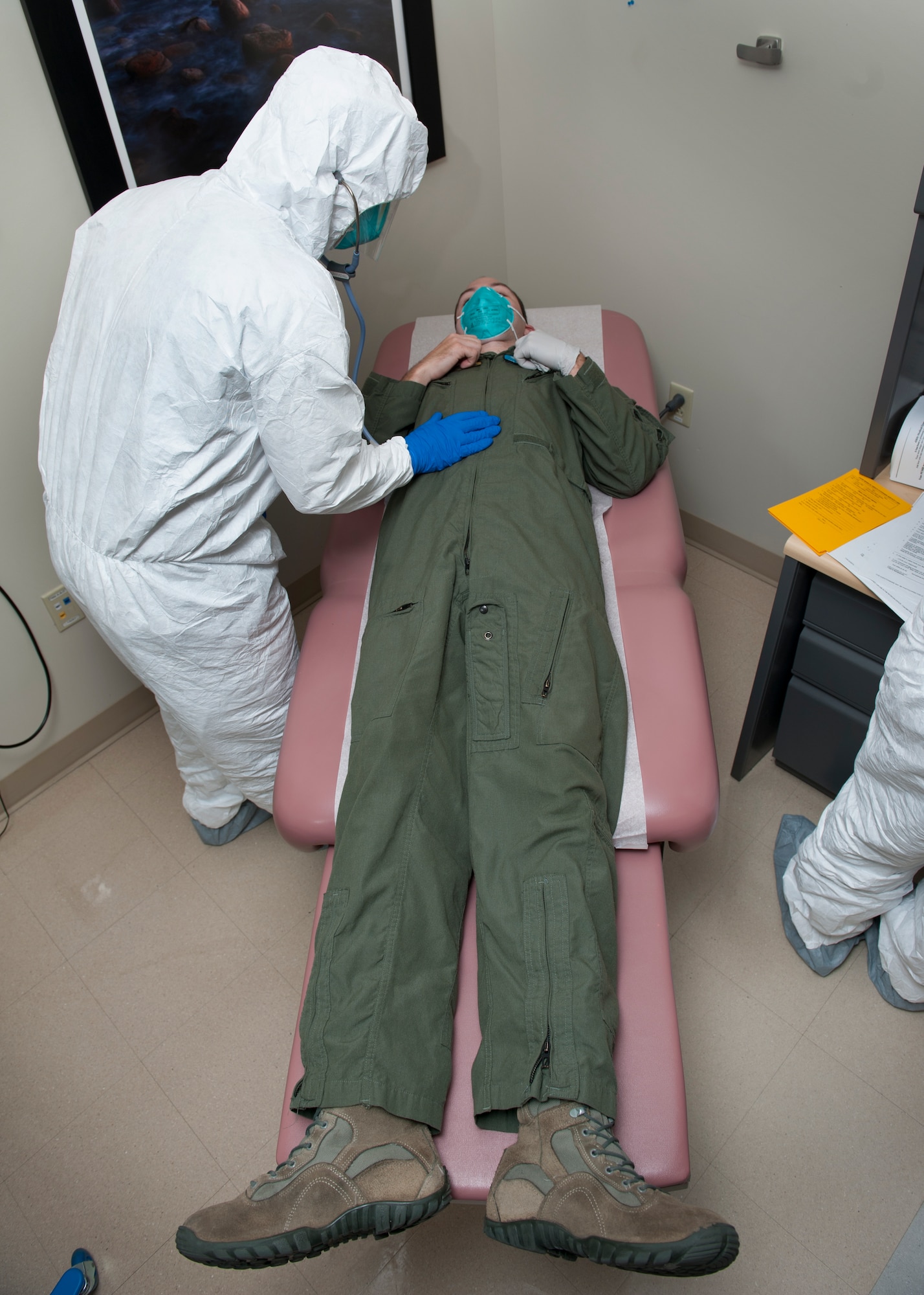 Maj. Troy Pearce, 436th Medical Operations Squadron staff physician, examines Senior Airman Peter Cannizzaro, 9th Airlift Squadron loadmaster, during an Ebola Response Plan and Transport exercise Nov. 3, 2015, at the 436th Medical Clinic on Dover Air Force Base, Del. The personnel of the medical clinic train regularly to prepare themselves to handle a real-word infectious disease scenario. (U.S. Air Force photo/Senior Airman Zachary Cacicia)