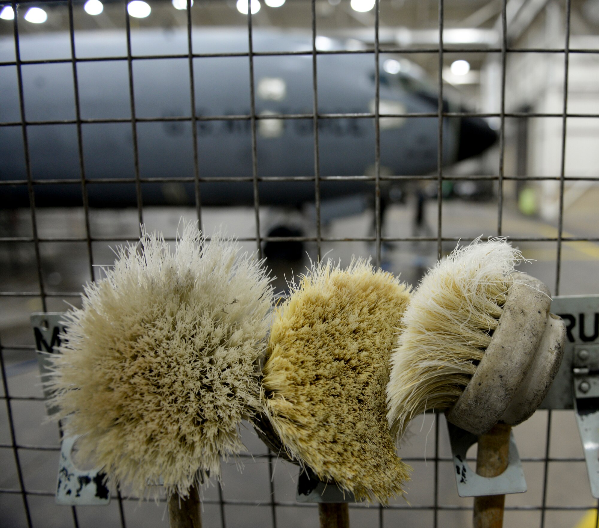 Scrub brushes hang in the wash-rack cage Nov. 23, 2015, on RAF Mildenhall, England. Along with brushes and sponge pads, the wash-rack cage houses proper protective equipment such as gloves, boots, suits, goggles and face shields so Airmen can be protected from the corrosive chemicals used to clean KC-135 Stratotankers. (U.S. Air Force photo by Staff Sgt. Micaiah Anthony/Released)