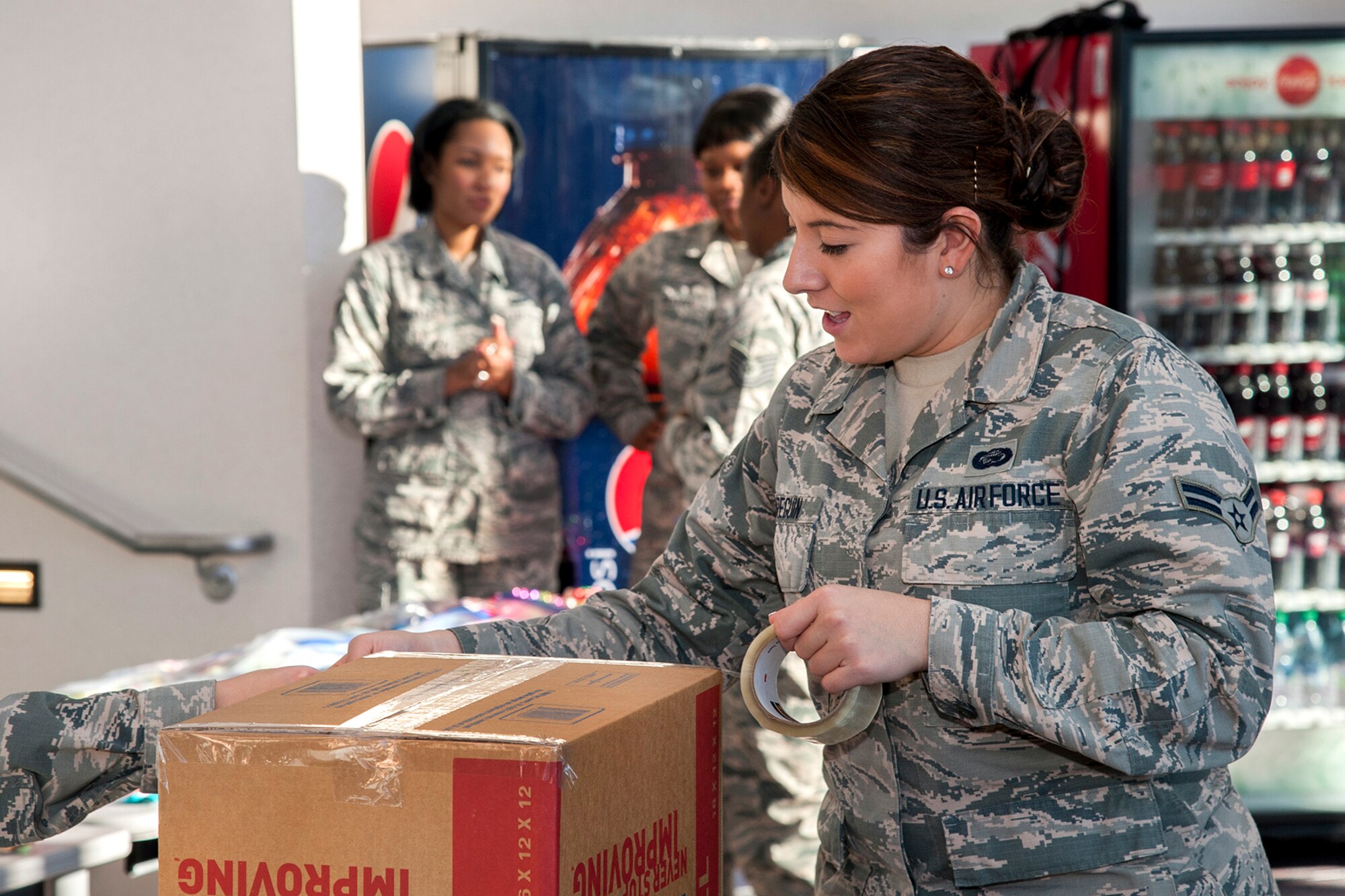 PETERSON AIR FORCE BASE, Colo. – Airman 1st Class Bianca Arreguin, 21st Force Support Squadron career development specialist, tapes a box filled with goodies for deployed service members, Nov. 18, 2015. A total of 12 large boxes were filled with items from lotions to candy and holiday decorations in support of the Operation Resolute Support Mission in Afghanistan. (U.S. Air Force photo by Craig Denton)
