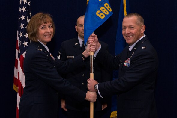 Col. Roger Vrooman, 688th Cyberspace Operations Group Commander, accepts the guidon for command of the group from Col. Michelle Hayworth, 688th Cyberspace Wing Commander, Dec. 1, 2015 at Scott Air Force Base, Ill. The group consists of five squadrons, the 835th and 837th at Scott, and the 833rd, 834th and 836th with the 688th Cyberspace Wing located at Joint Base San Antonio-Lackland, San Antonio, Texas. (U.S. Air Force Photo/Senior Airman Joshua Eikren)