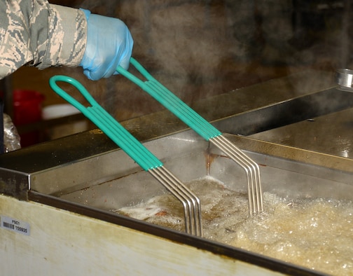 U.S. Air Force Staff Sgt. Christopher Williams, 100th Force Support Squadron Gateway Dining Facility shift supervisor, prepares food to be served during lunch Nov. 23, 2015, on RAF Mildenhall, England. The military members who work at the facility are also rotated to the fitness centers, lodging, and readiness to expand their skills in the services career field. (U.S. Air Force photo by Gina Randall/Released)