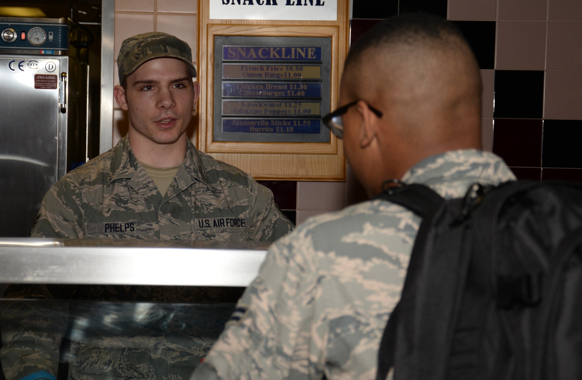 U.S. Air Force Senior Airman Jacob Phelps, left, 100th Force Support Squadron Gateway Dining Facility food service journeyman, takes a food order from a customer during lunch Nov. 23, 2015, on RAF Mildenhall, England. Many Airmen who reside in the dormitories have meals in the facility on base. Dormitory residents are given meal cards to use to buy food in the facility. (U.S. Air Force photo by Gina Randall/Released)