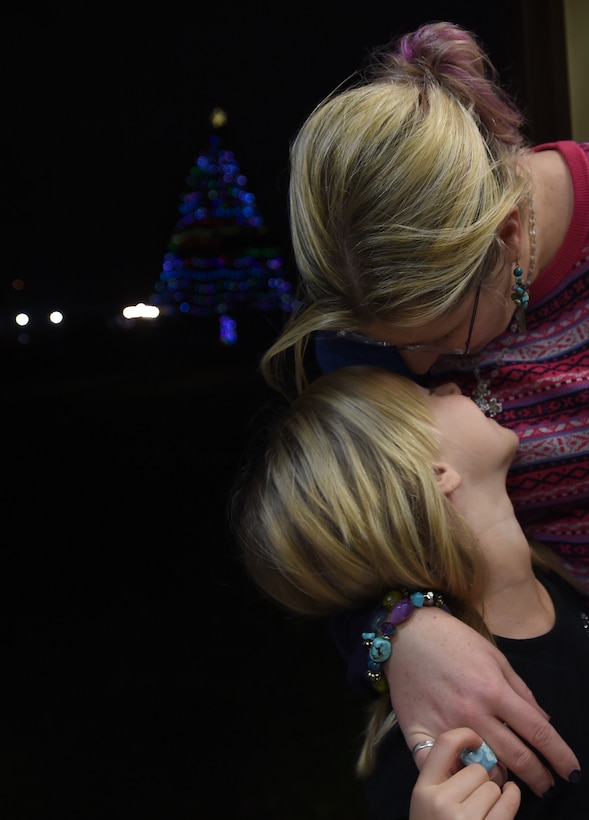 A mother leans in to kiss her daughter’s head during the Christmas tree and Menorah Lighting Ceremony at Joint Base Andrews, Md., Dec. 2, 2015. Approximately 100 people attended the annual chapel holiday event. (U.S. Air Force photo/ Senior Airman Nesha Humes)