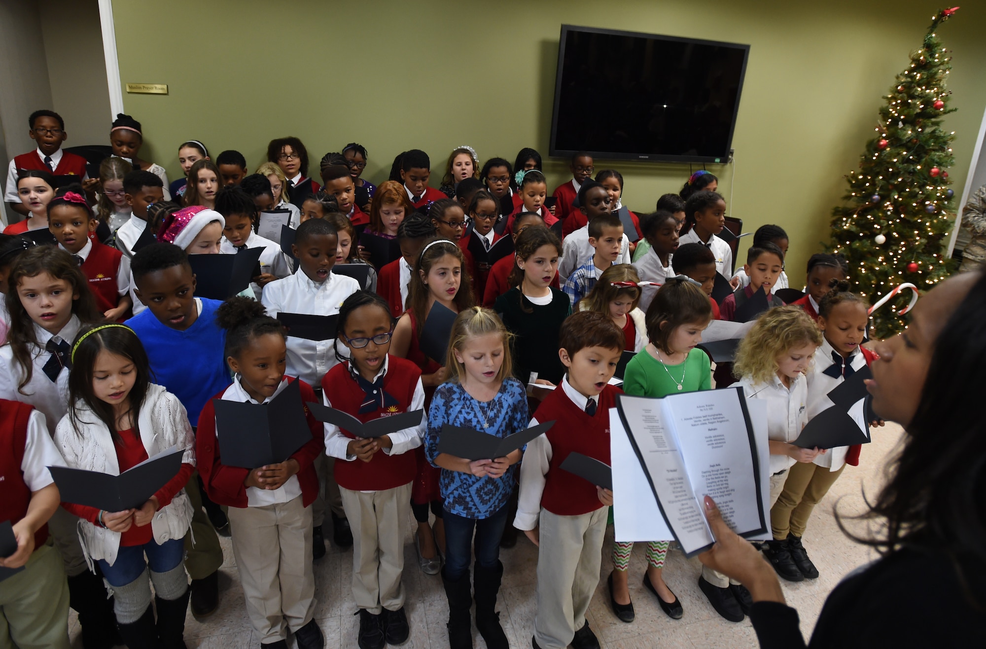 Imagine Andrews choir students sing holiday songs for Joint Base Andrews families during the annual Christmas Tree and Menorah Lighting ceremony at Joint Base Andrews, Md., Dec. 2, 2015. Approximately 100 people attended the annual chapel holiday event.  (U.S. Air Force photo/ Senior Airman Nesha Humes)