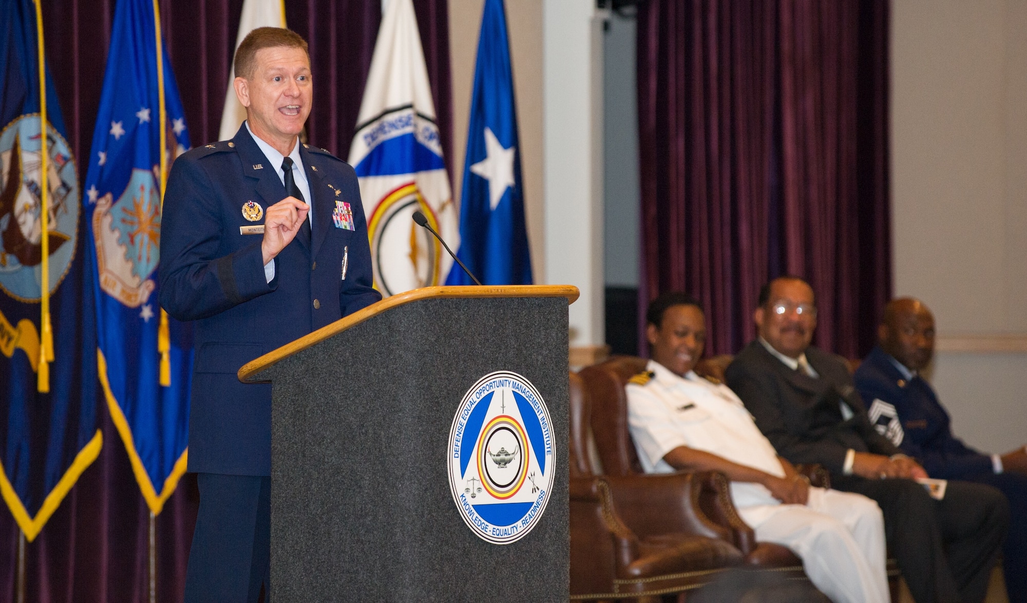 Brig. Gen. Wayne R. Monteith, 45th Space Wing commander, speaks to members of Class 15-3 while giving the graduation speech for the final Equal Opportunity Advisors Course of 2015 at the Defense Equal Opportunity Management Institute  at Patrick Air Force Base, Fla. Joining Monteith in the official party on stage for the Class 15-3 ceremony from DEOMI were (left to right) Commander Yolanda K. Mason, Acting Commandant, Dr. Jose Bolton, Dean of Equal Opportunity and Equal Employment Opportunity and Chief Master Sgt. Boston Alexander, Senior Enlisted Advisor. (U.S. Air Force photo/Benjamin Thacker/Released) 