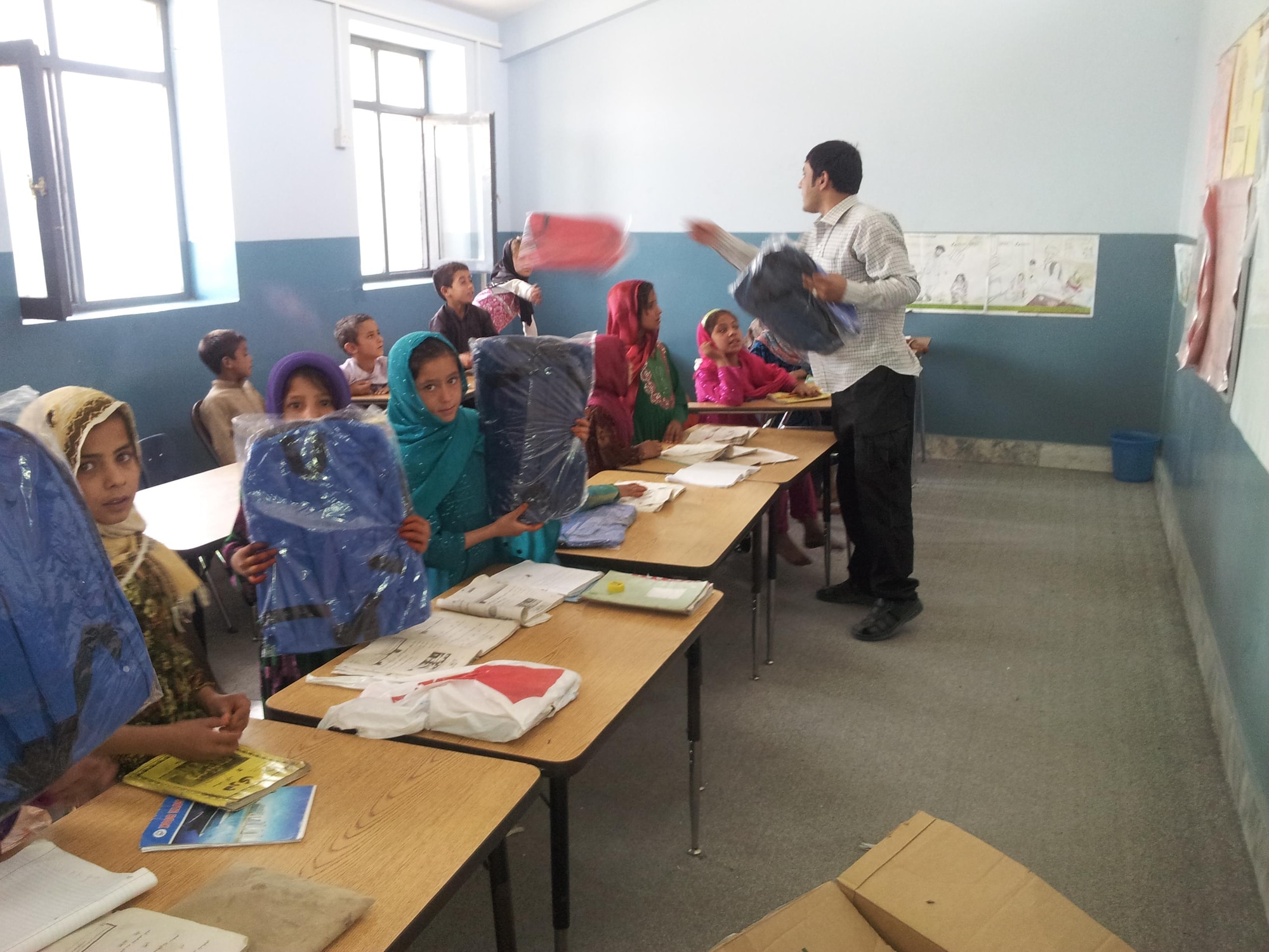 A volunteer at an orphanage in Kabul, Afghanistan, passes out school supplies donated by family and friends of U.S. Army Staff Sgt. Matthew Amon, a security forces squad leader at Train, Advise, Assist Command-Air (TAAC-Air). Amon met the orphanage project manager and became friends, and soon realized there was a need for supplies. (U.S. Air Force courtesy photo/released)