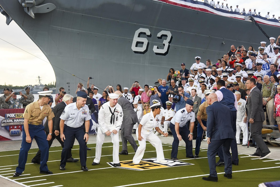 U.S. service members re-enact a football play with Fox NFL Sunday hosts at the Battleship Missouri Memorial on Joint Base Pearl Harbor-Hickam, Hawaii, Dec. 6, 2015. Fox NFL Sunday was at the base to commemorate the 74th anniversary of the attack on Pearl Harbor. U.S. Navy photo by Petty Officer 2nd Class Brian M. Wilbur