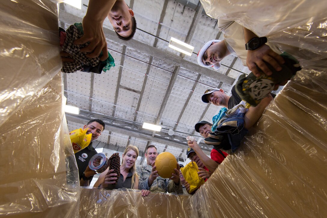 (Center) Brig. Gen. Andrew Toth, 36th Wing Group commander, and volunteers throughout the local community place relief items into a box while sorting donations for Operation Christmas Drop at Andersen Air Force Base, Guam, Dec. 5, 2015. More than 40,000 pounds of goods will be dropped to 56 islands throughout the Commonwealth of the Northern Marianas, Federated States of Micronesia and Republic of Palau during Operation Christmas Drop 2015, the longest running Department of Defense humanitarian airdrop mission. (U.S. Air Force photo by Osakabe Yasuo/Released)