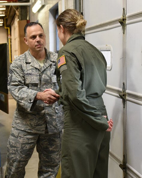 Chief Master Sgt. Matthew Caruso, command chief, Air Force Special Operations Command, coins Staff Sgt. Nicole Gentzel, airborne mission systems specialist, 193rd Special Operations Group, Feb. 8, 2015. Gentzel's aviation skills and dedicated leadership have paved the path for other Airmen to emulate as she has won recognition at the Wing, State and Major Command level.  (U.S. Air National Guard photo by Airman First Class Julia Sorber/Released)