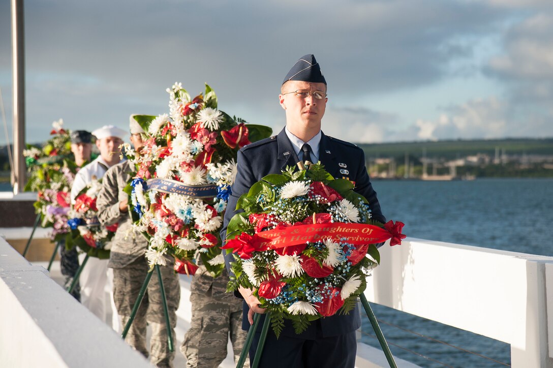 Service members carry ceremonial wreaths to be presented to the entombed crew of the USS Utah during the USS Utah Memorial sunset tribute at Ford Island, Joint Base Pearl Harbor-Hickam, Hawaii, Dec. 6, 2015. U.S. Navy photo by Petty Officer 2nd Class Gabrielle Joyner