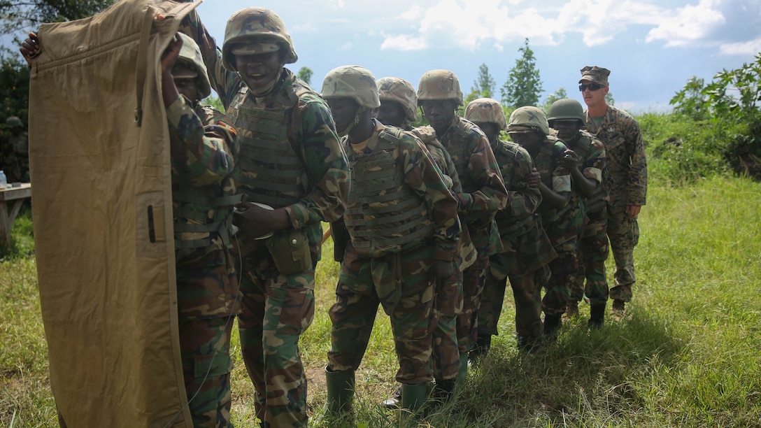 A Uganda People’s Defense Force soldier (second from left), acts as breacher and pulls the safety off an igniter as instructed by U.S. Marine Sgt. Sam Adkins (far right), an explosive ordnance disposal technician with Special-Purpose Marine Air-Ground Task Force Crisis Response-Africa, during a practice breaching drill at Camp Singo, Uganda, Nov. 24, 2015. The Marines and UPDF improved breaching capabilities as they prepare for their African Union Mission in Somalia 