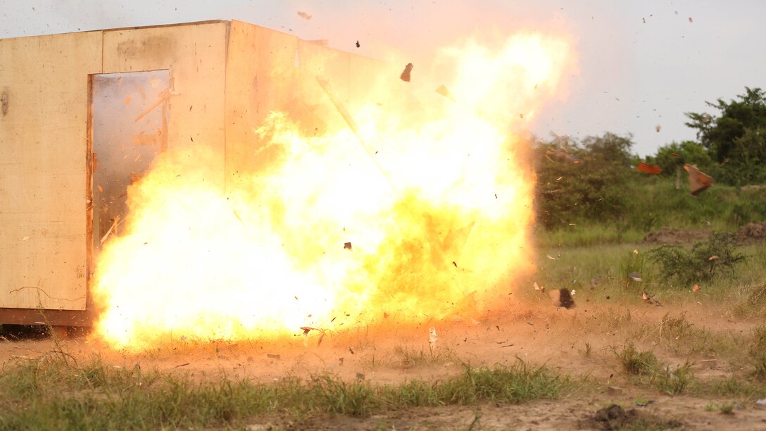 A Uganda’s People Defense Force soldier detonates an oval charge on the wall of a notional objective position of desired entry while the team seeks cover around the corner of the position at Camp Singo, Uganda Nov. 25, 2015. This type of charge is used to create a hole through a wall when there is no available entrance or to gain the element of surprise. The Marines and UPDF improved breaching capabilities as they prepare for their African Union Mission in Somalia. 