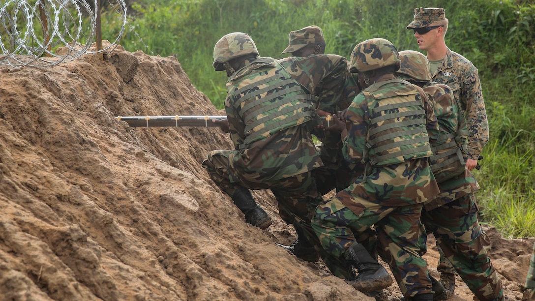 U.S. Marine Sgt. Sam Adkins, an explosive ordnance disposal technician with Special-Purpose Marine Air-Ground Task Force Crisis Response-Africa and Uganda People’s Defense Force soldiers emplace explosives through the dirt during a breaching exercise at Camp Singo, Uganda, Dec. 1, 2015. The goal is to breach the obstacle by eliminating the razor wire and creating a hole in the man-made dirt wall. The Marines and UPDF improved breaching capabilities as they prepare for their African Union Mission in Somalia.