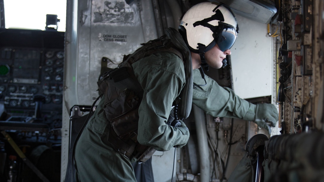 A Marine with Marine Heavy Helicopter Squadron 361 peers out of a hatch of a CH-53E Super Stallion while flying over Marine Corps Air Station Miramar, Calif., Dec. 2. Marines with HMH-361 conducted section Confined Area Landings and Field Carrier Landing Practices to fulfill training requirements for landing aboard a Navy ship. 