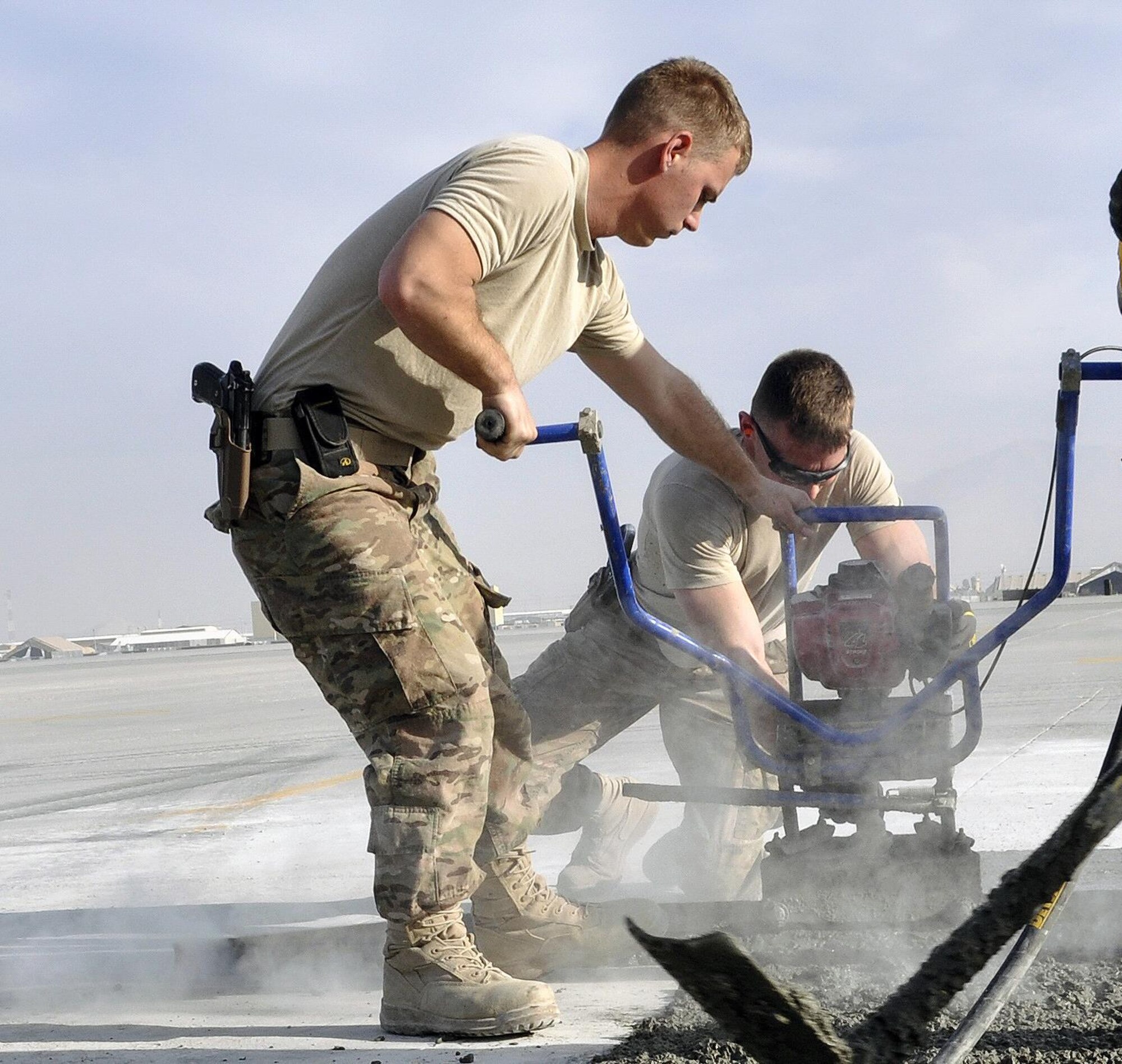 Airmen from the 455th Expeditionary Civil Engineer Squadron get ready for another batch of cement to repair a section of the flightline at Bagram Airfield, Afghanistan, Dec. 7, 2015. Airfield integrity concerns are reviewed twice a month by Airfield Management and 455th ECES. Once repairs are completed, these areas of the flightline should not require maintenance for up to 10 years.  (U.S. Air Force photo by Tech. Sgt. Nicholas Rau/Released)