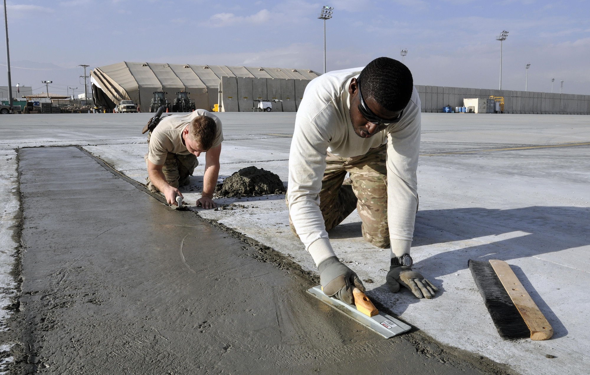 Staff Sgt. Richard Bonham, and Airman 1st Class Alex Gromley, both from the 455th Expeditionary Civil Engineer Squadron, smooth out the edges of cement during a repair of a section of the flightline at Bagram Airfield, Afghanistan, Dec. 7, 2015.   Airfield integrity concerns are reviewed twice a month by Airfield Management and 455th ECES. Once repairs are completed, these areas of the flightline should not require maintenance for up to 10 years.  (U.S. Air Force photo by Tech. Sgt. Nicholas Rau/Released)