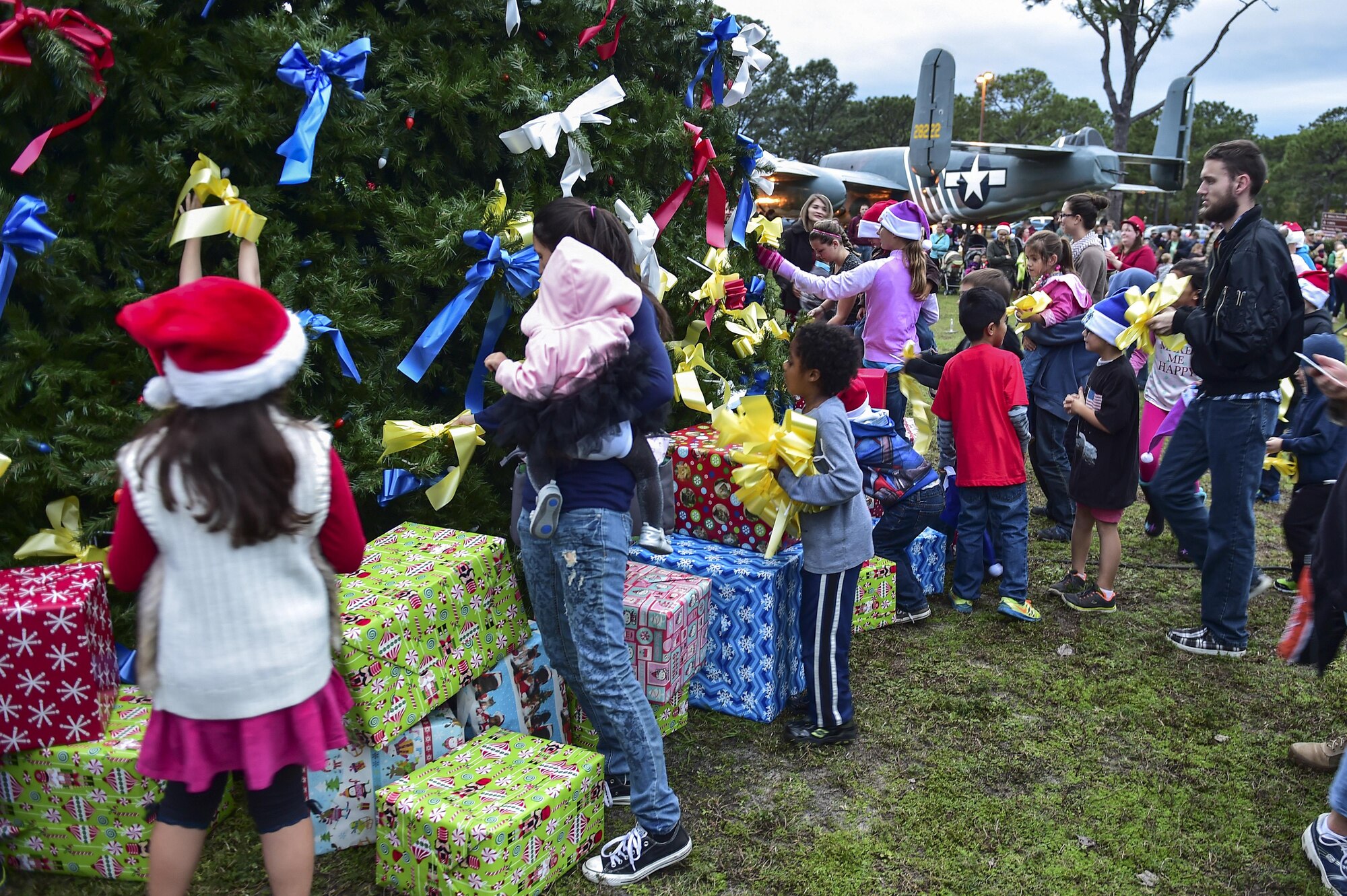 Families place yellow ribbons on the Christmas tree during the annual Christmas tree lighting ceremony at Hurlburt Field, Fla., Dec. 2, 2015. The yellow ribbons symbolize remembering their loved ones who are deployed during this holiday season. (U.S. Air Force photo by Senior Airman Jeff Parkinson)