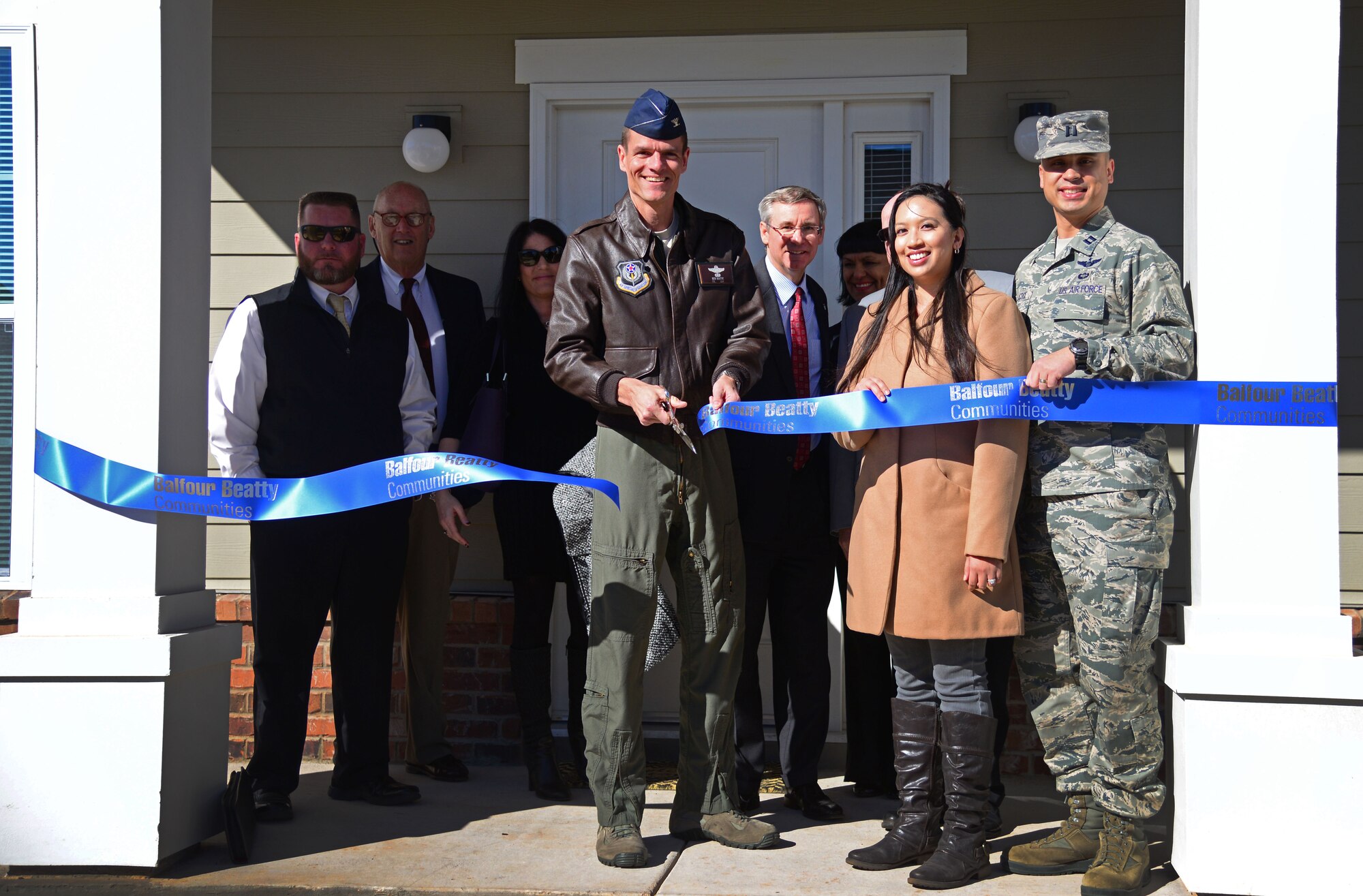 U.S. Air Force Col. Ben Maitre, 27th Special Operations Wing commander, cuts a ceremonial ribbon with Capt. Rex Peacock, 27th Special Operations Air Operations Squadron, and his wife in front of the couple’s new home Dec. 3, 2015, at Cannon Air Force Base, N.M. Balfour Beatty Communities held the ribbon cutting ceremony to mark the completion of their first new company grade officer houses on base. (U.S. Air Force photo/Staff Sgt. Alexx Pons) 