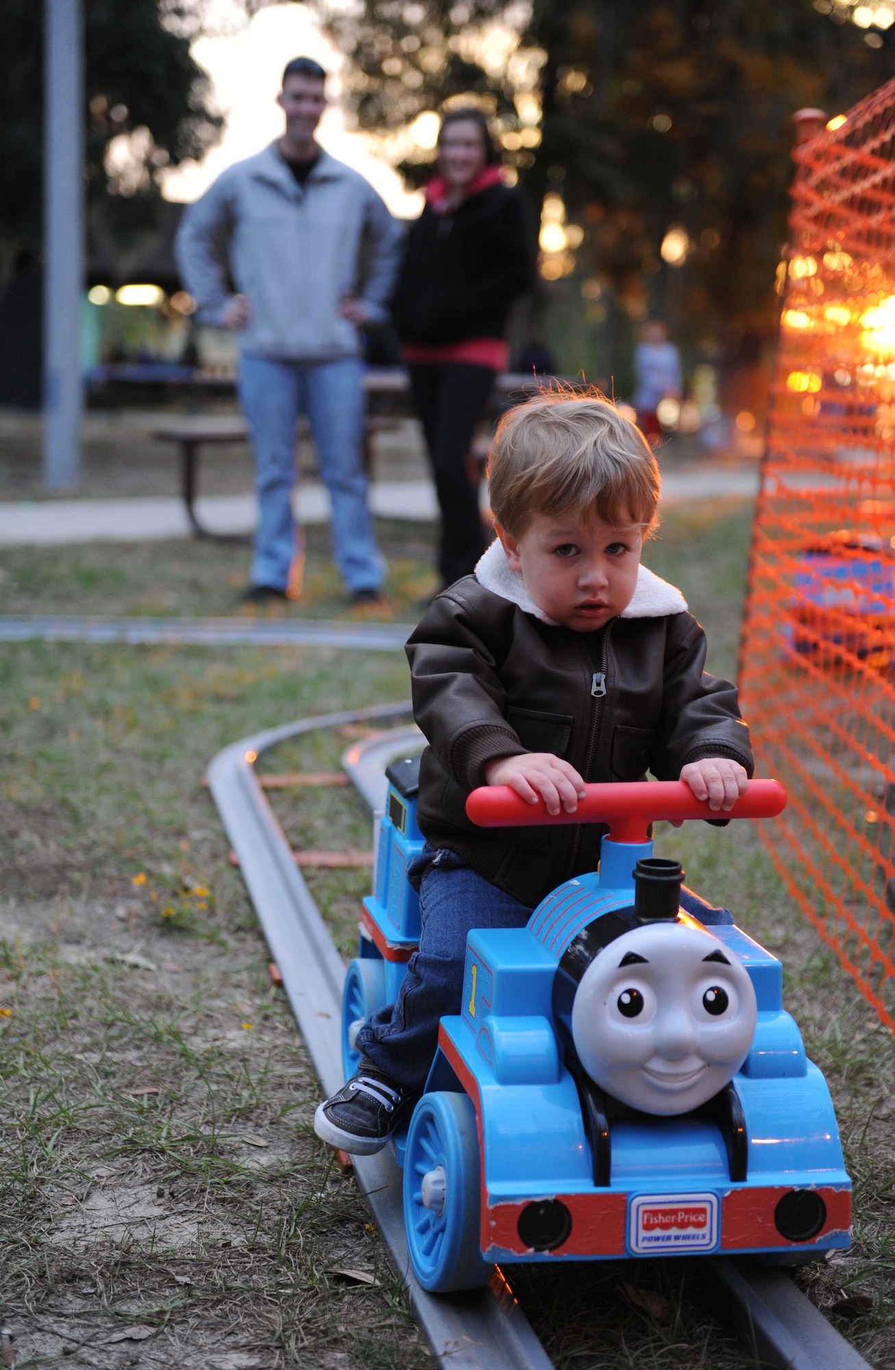 Tech. Sgt. Darryl Weaver, 336th Training Squadron military training leader, and his wife, Amber, watch their son, Aiden, as he rides a motorized toy train during Keesler’s annual Christmas in the Park celebration at marina park Dec. 3, 2015, Keesler Air Force Base, Miss. The event, hosted by Outdoor Recreation, included a tree lighting ceremony, tour train rides, holiday music, cookie and ornament decorating, and visits with Santa. (U.S. Air Force photo by Kemberly Groue)